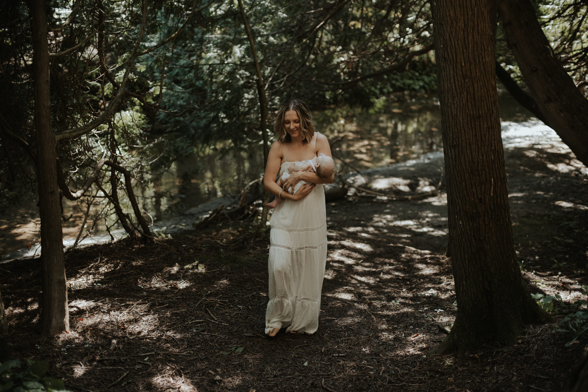 Mother carrying newborn daughter in a forest