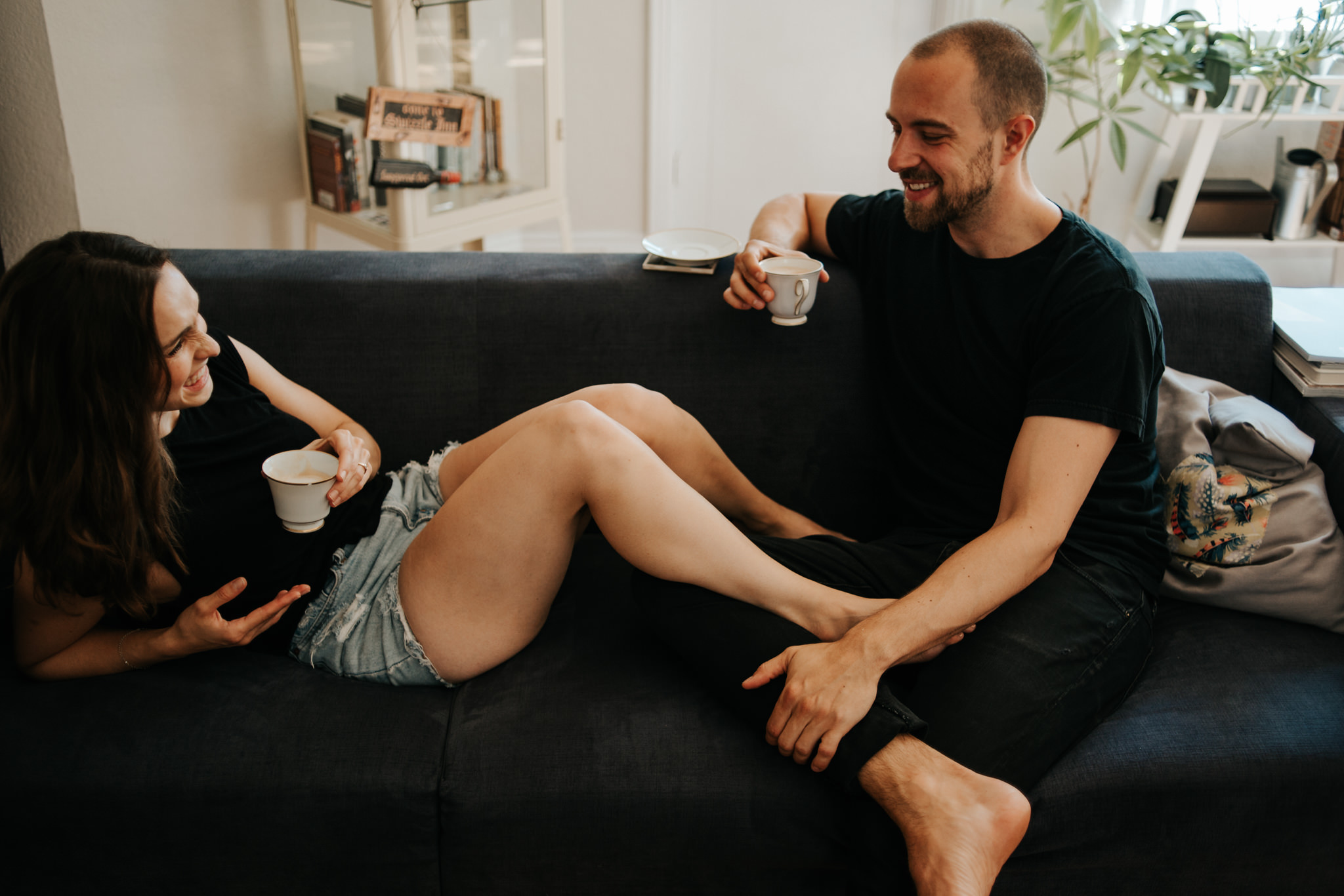 Couple laughing and sitting on couch with coffee