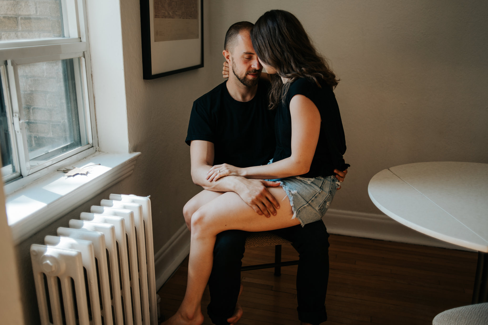 Intimate moment between couple as they hug at kitchen table