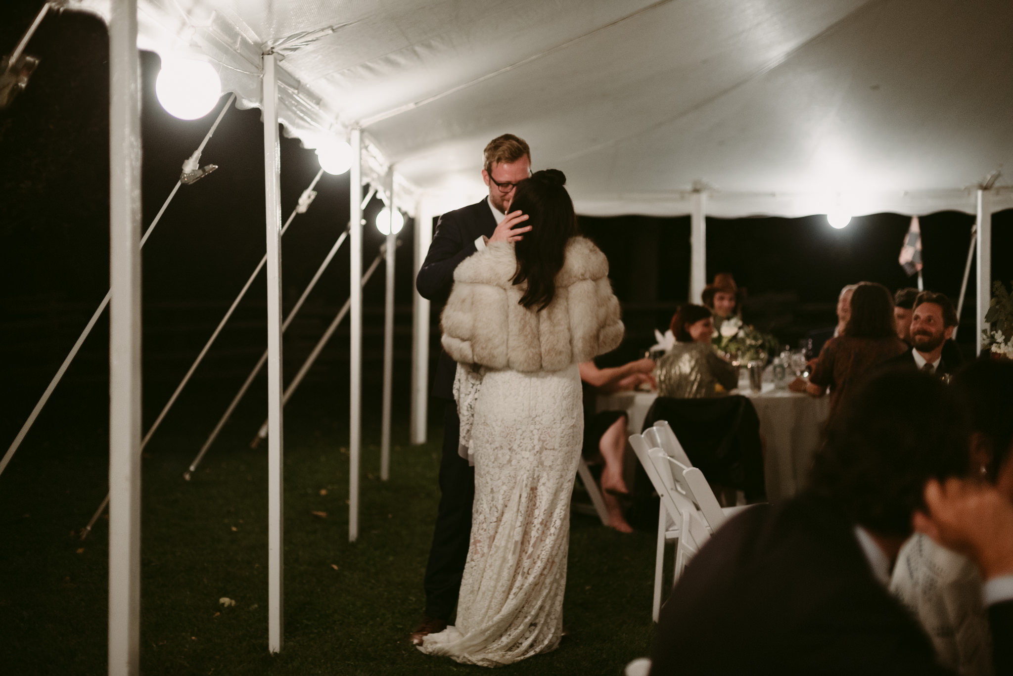 Bride and groom kissing in tent at wedding reception