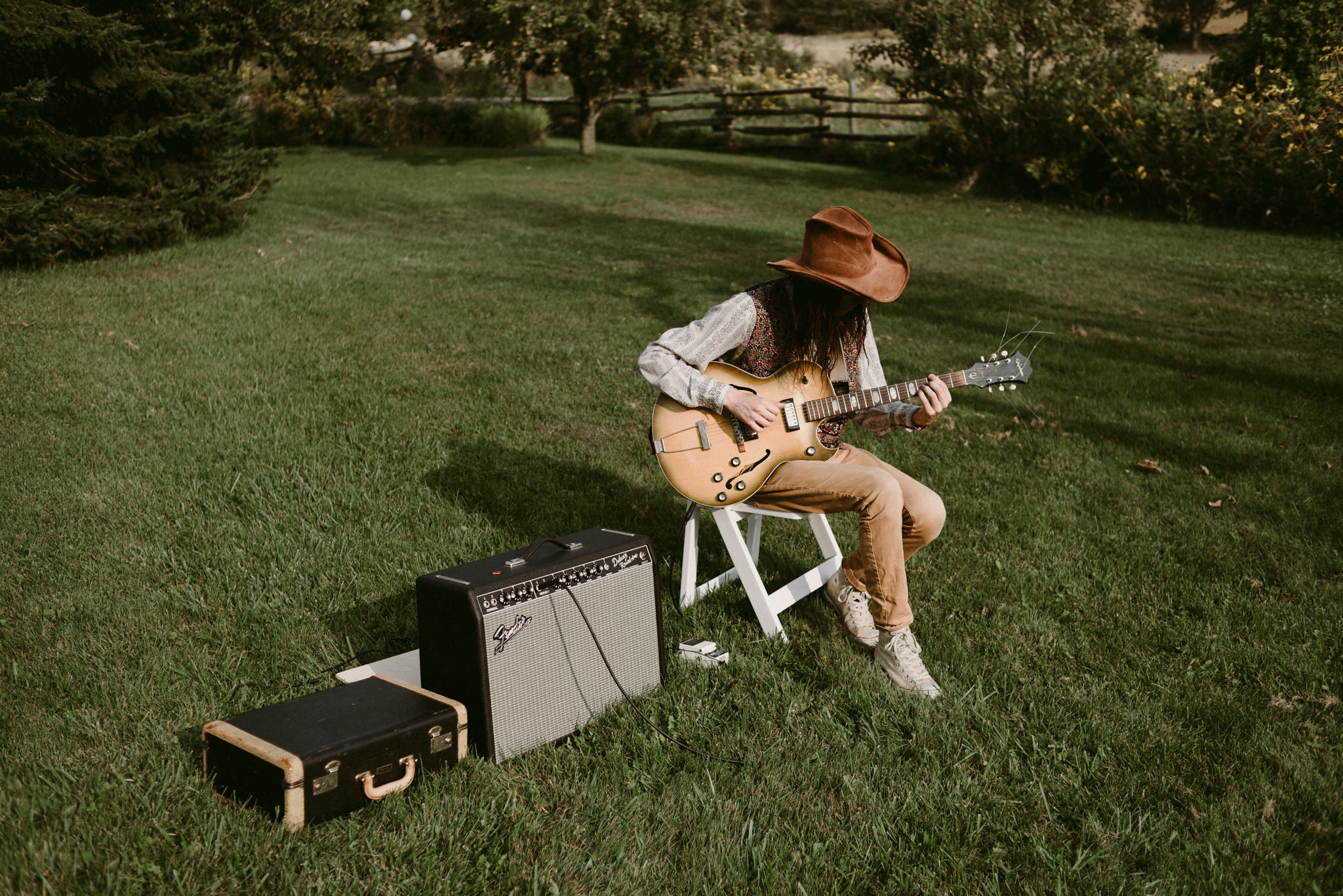 Hipster musician playing guitar at outdoor backyard wedding ceremony