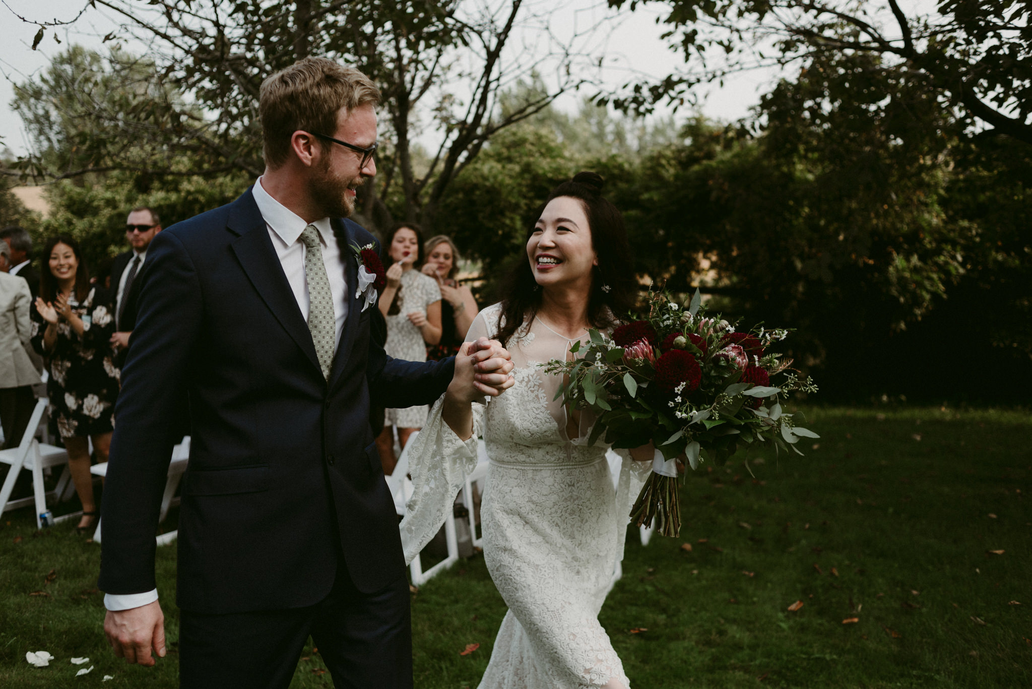 bride smiling at groom walking down aisle after outdoor backyard wedding ceremony