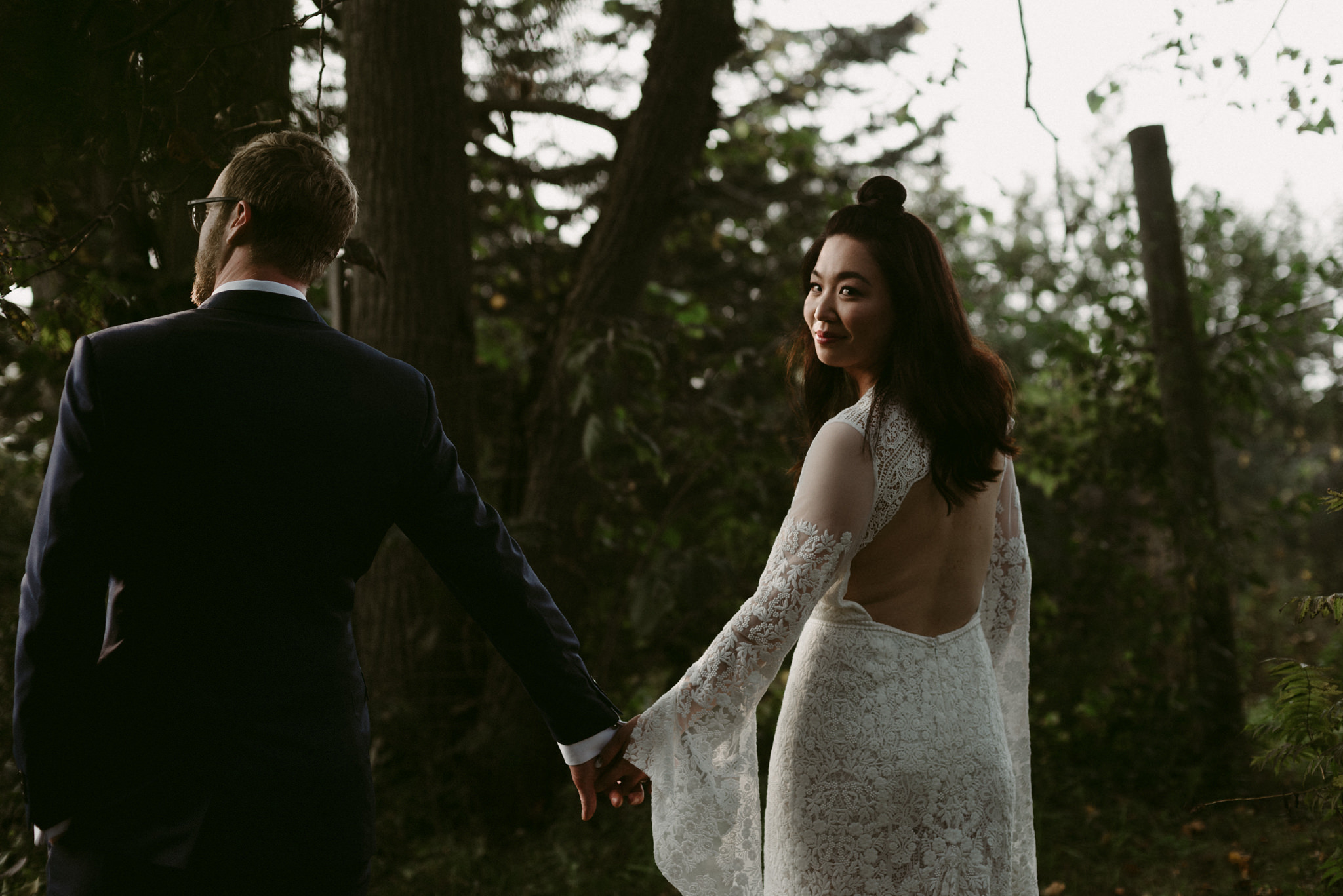 Bride looking back as she holds grooms hand