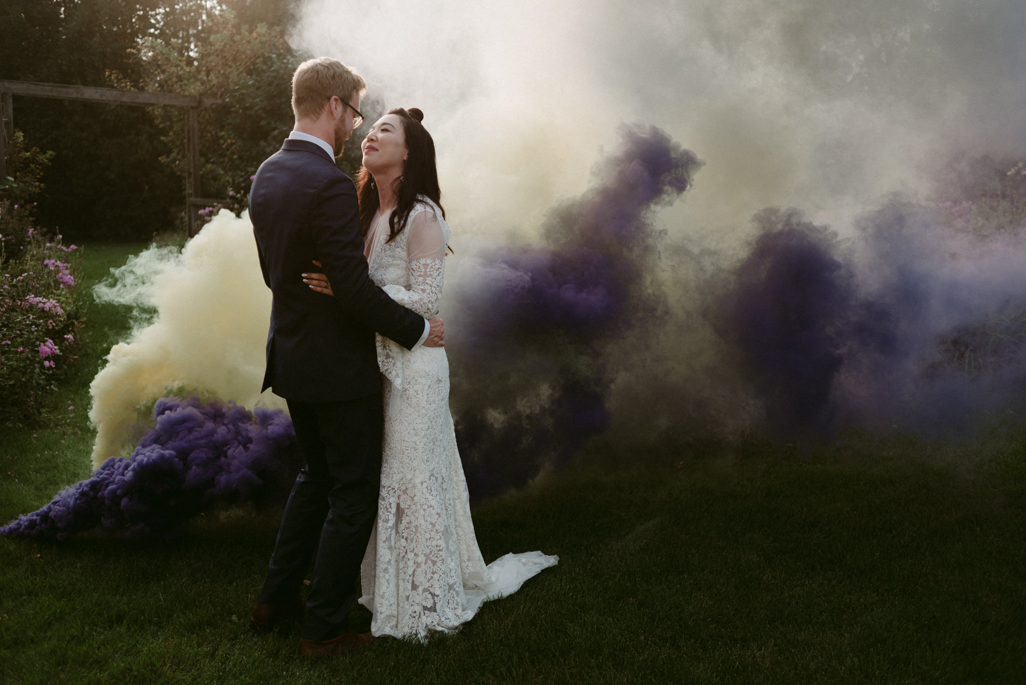 bride and groom kissing with smoke bombs around them