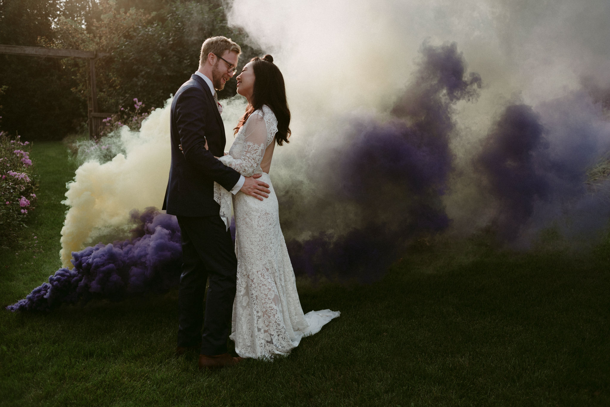 bride and groom kissing with smoke bombs around them