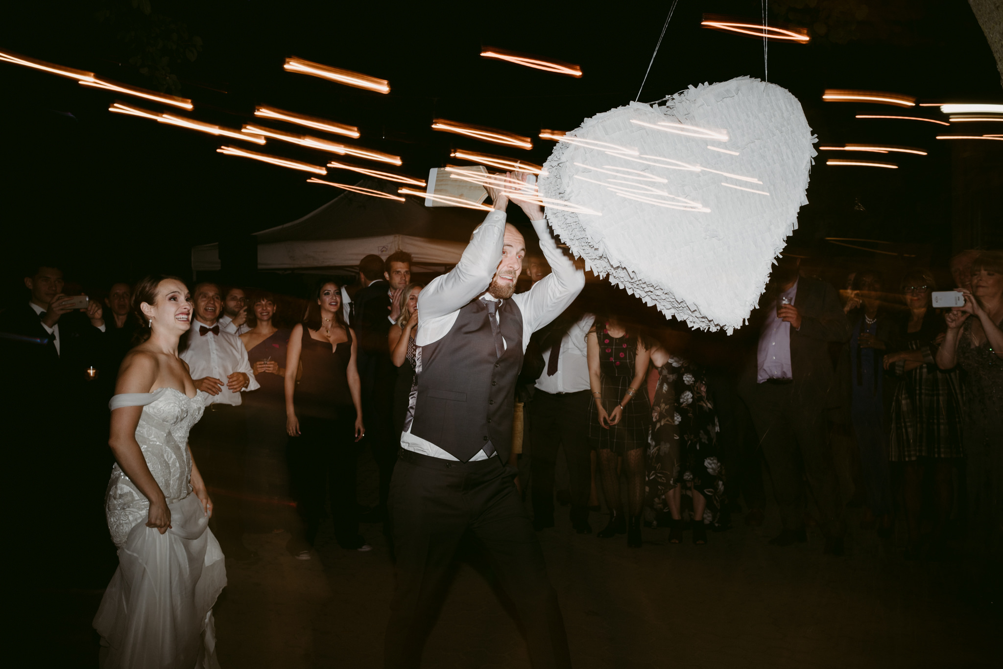 Groom hitting piñata at wedding