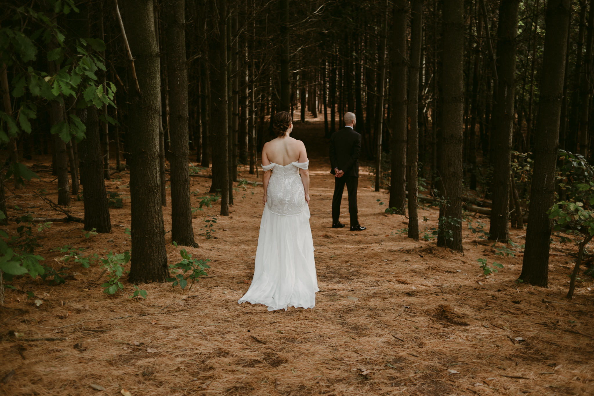 Bride walking towards groom in forest at Kortright Centre for Conservation