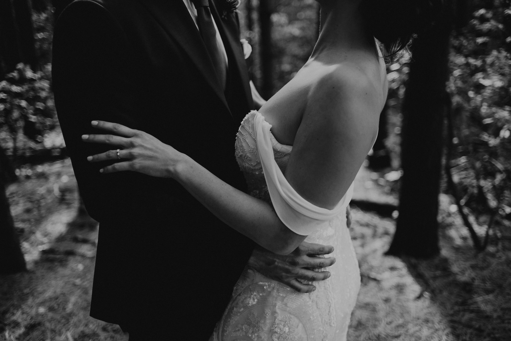 Black and white images of groom hugging bride in beautiful off the shoulder wedding dress