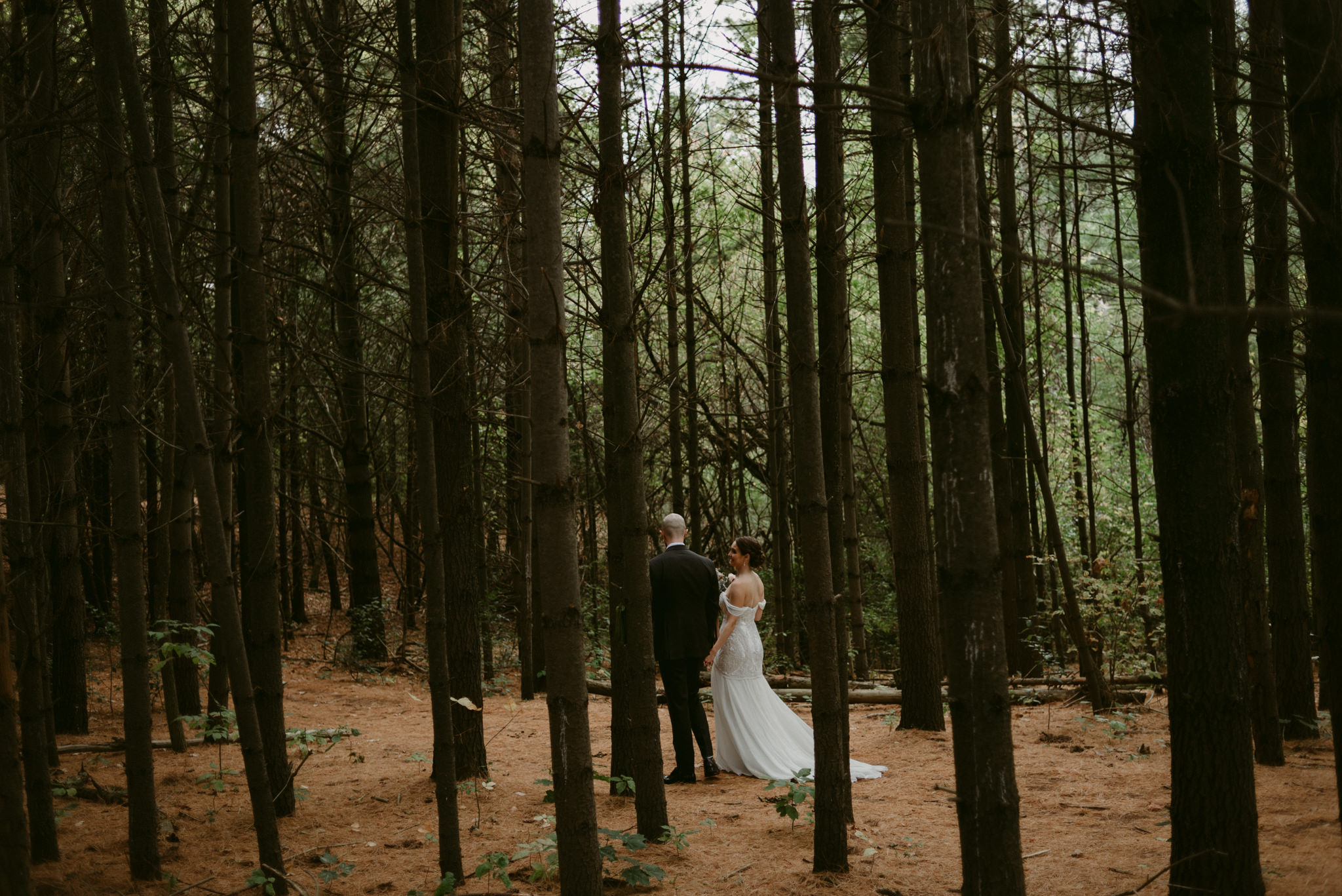 Bride and groom holding hands and walking in forest