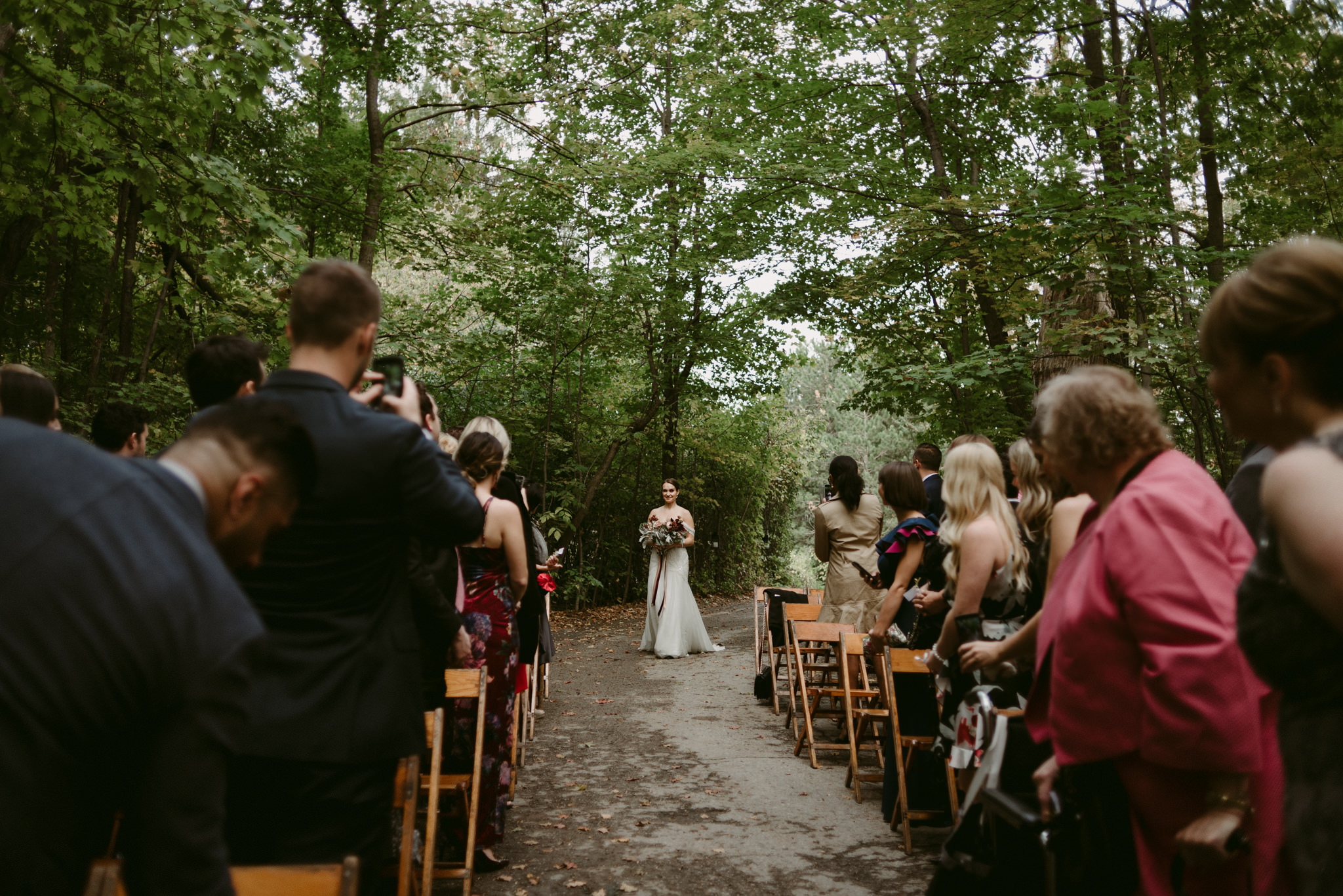 Bride walking down aisle by herself in forest wedding ceremony