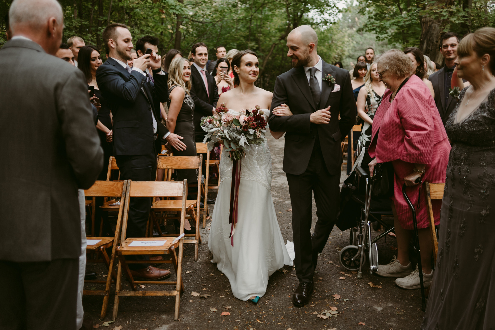 Groom walking bride down aisle in outside wedding ceremony