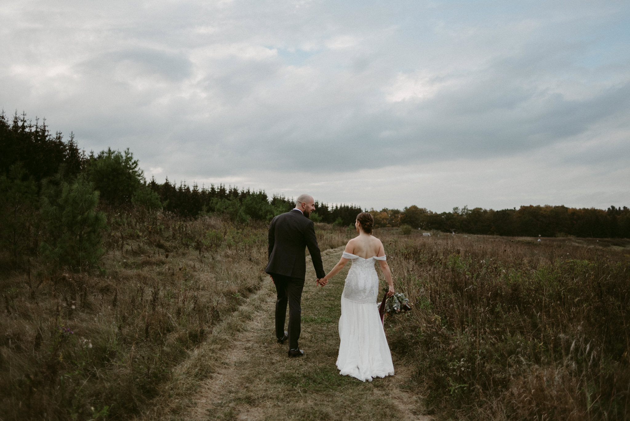 Bride and groom walking in field