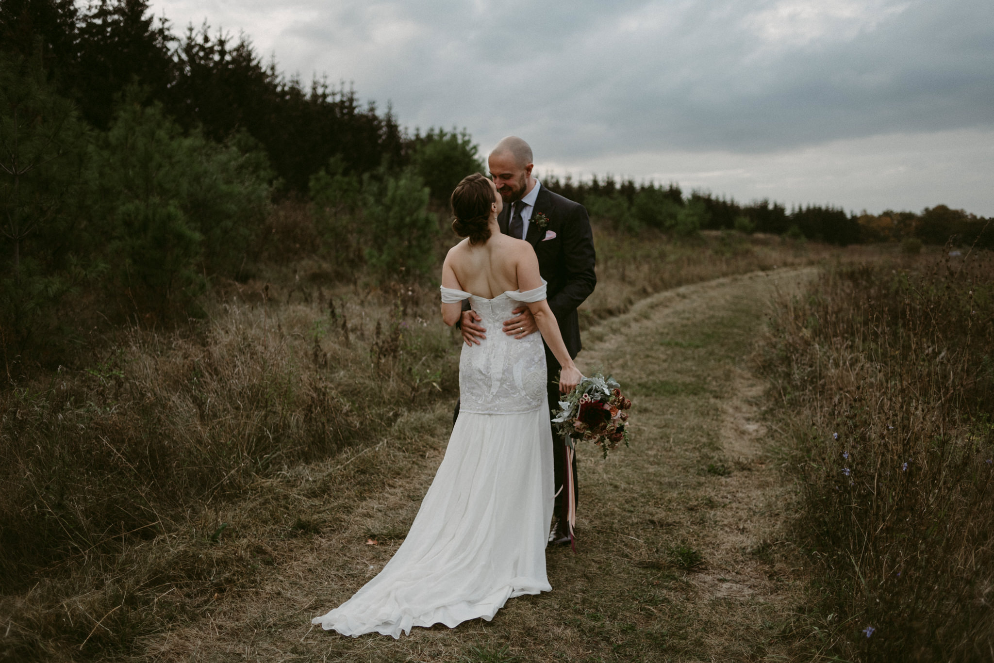 Bride and groom kissing in field