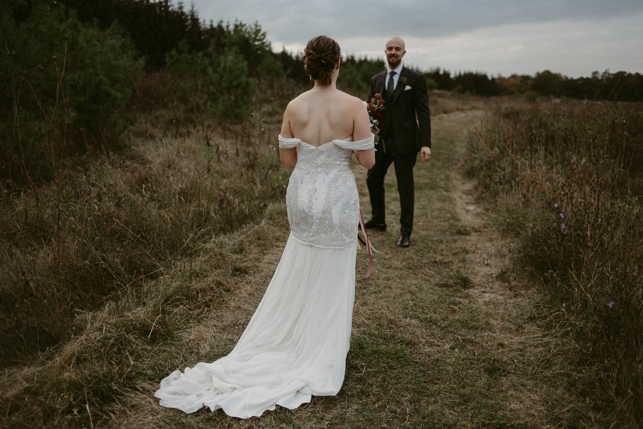 Bride walking towards groom in field