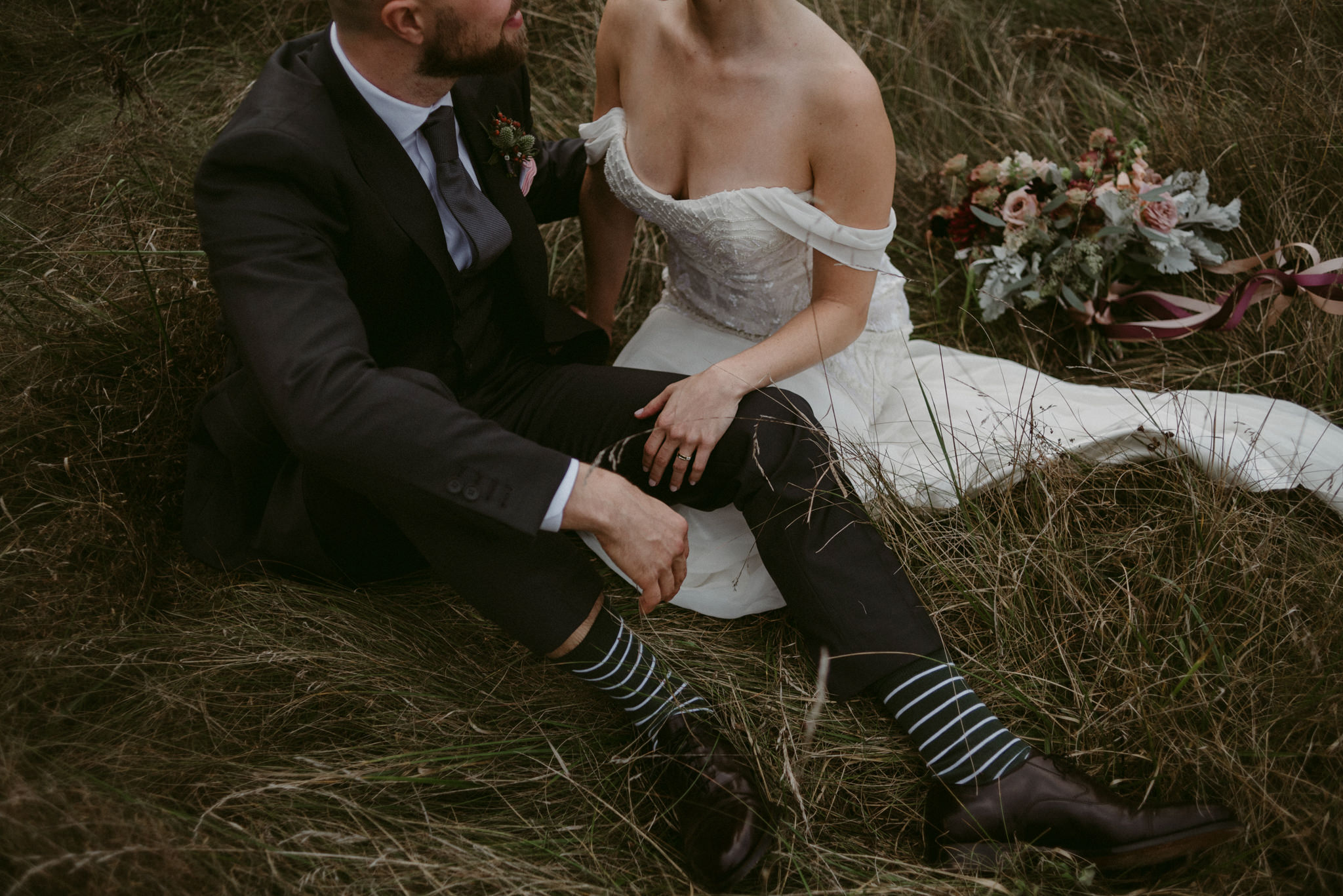 Bride and groom sitting in field