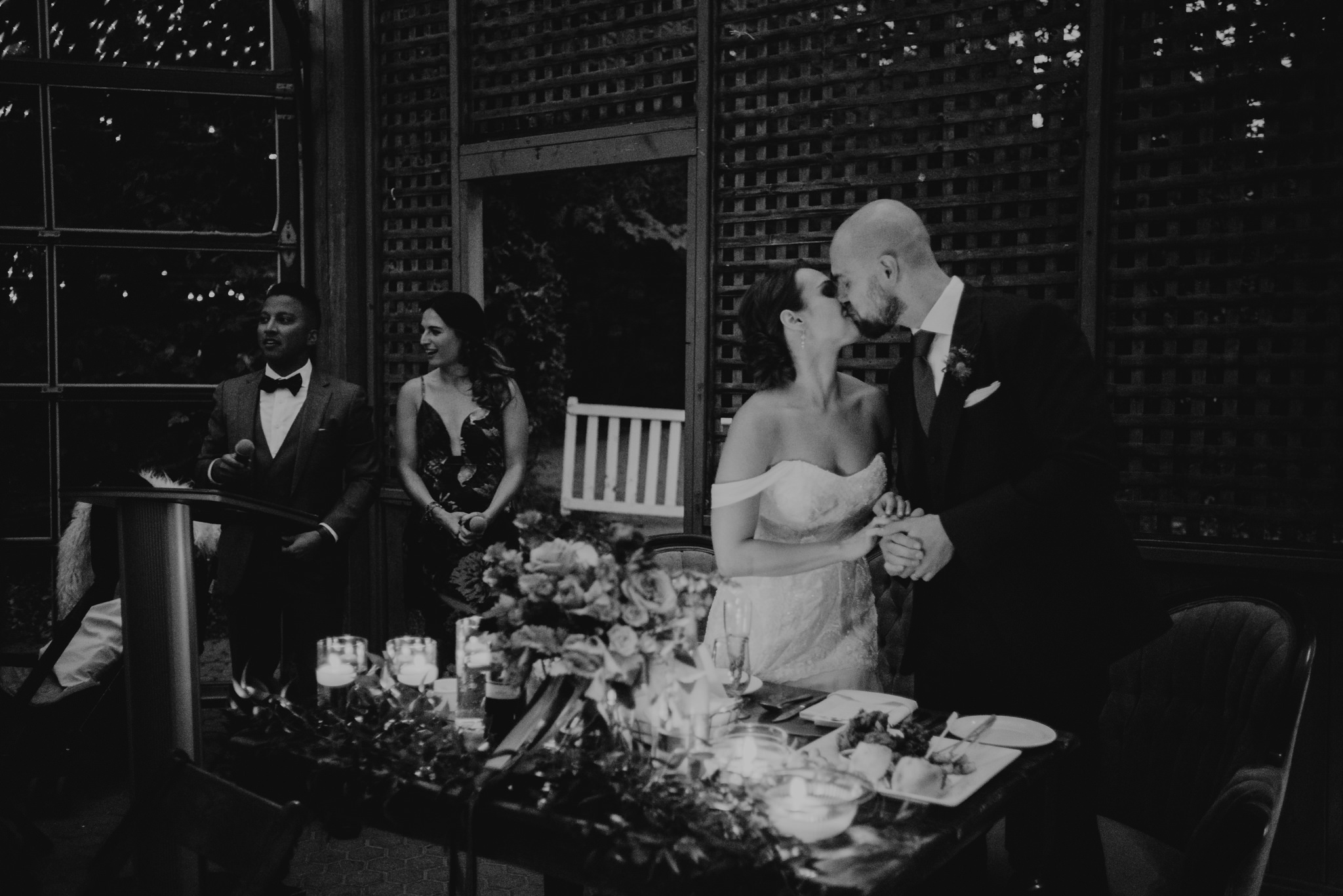 black and white of bride and groom kissing during wedding reception