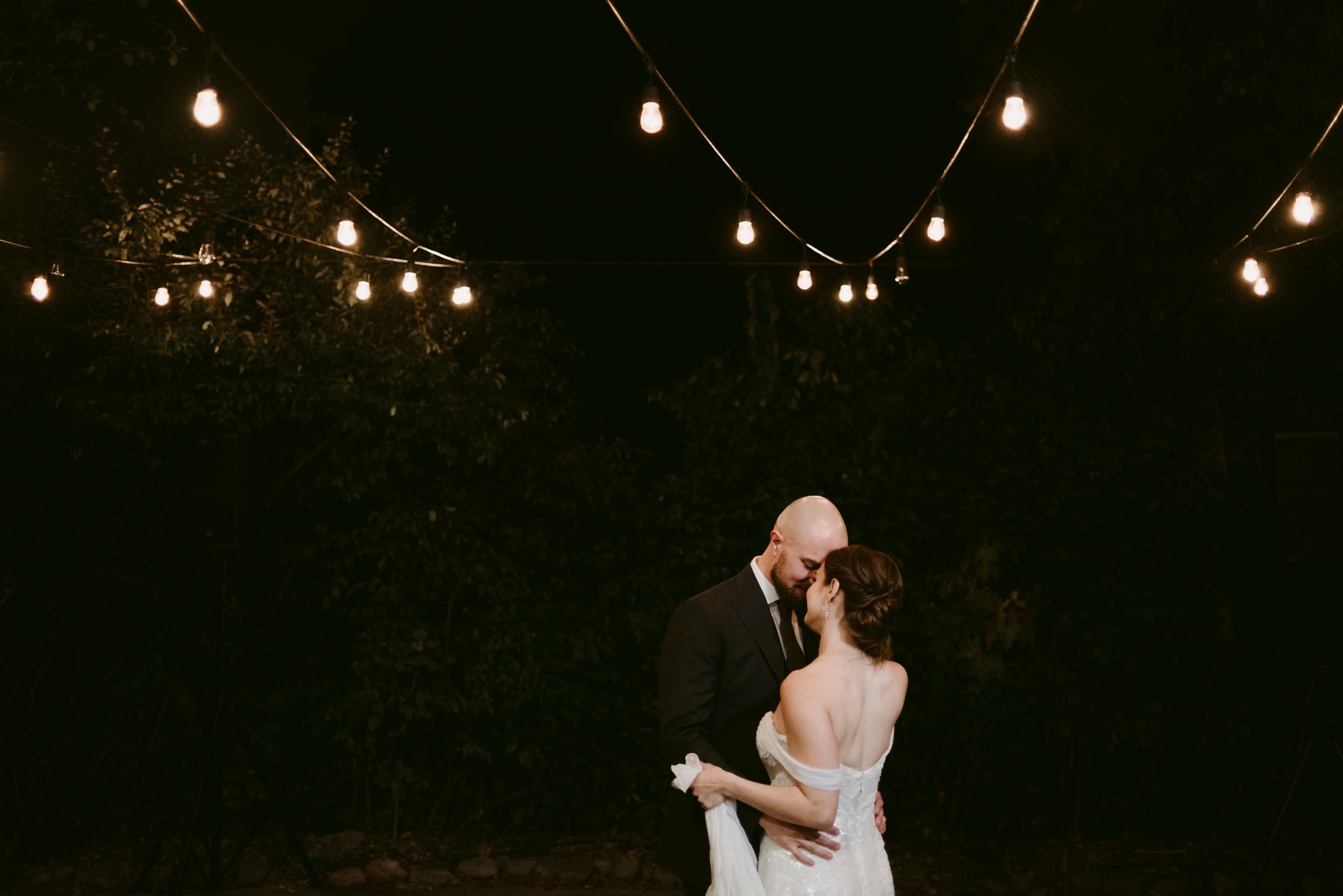 Bride and groom dancing under string lights