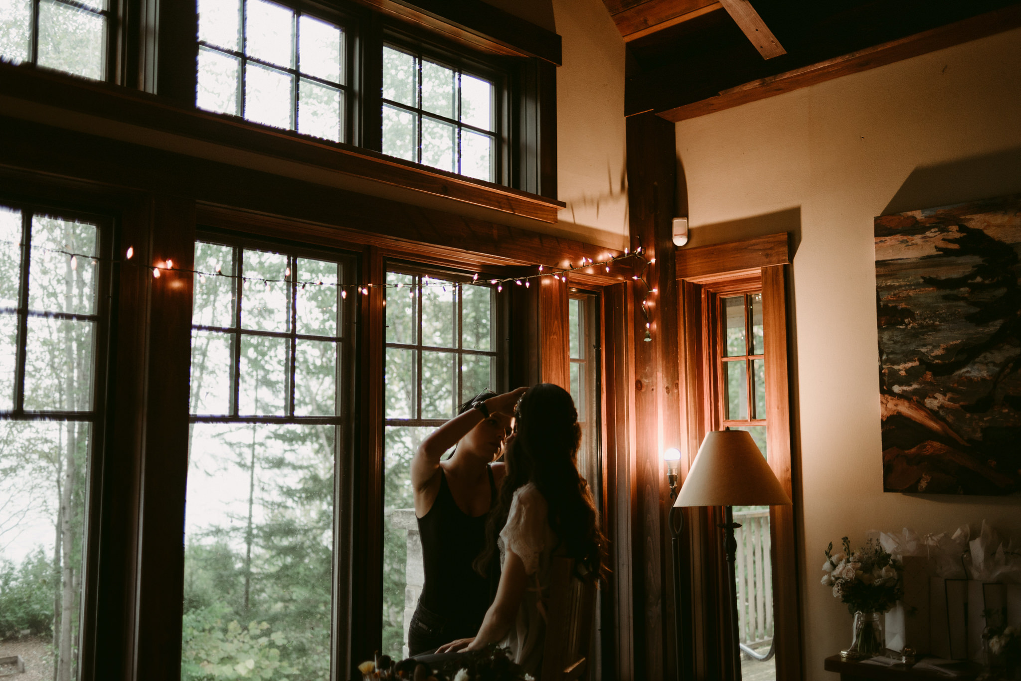 Bride getting makeup done by window at cottage