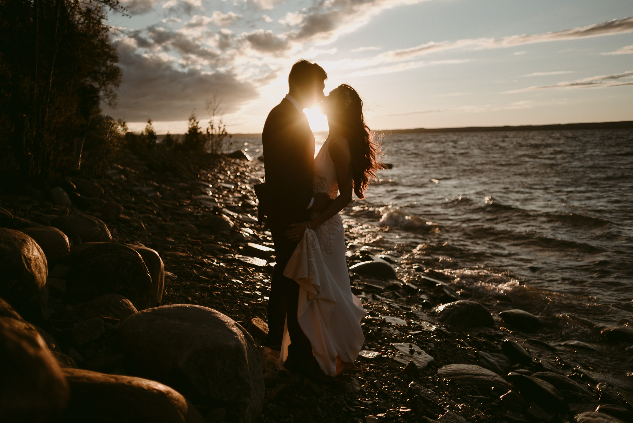 bride and groom kissing by water at sunset on georgian bay