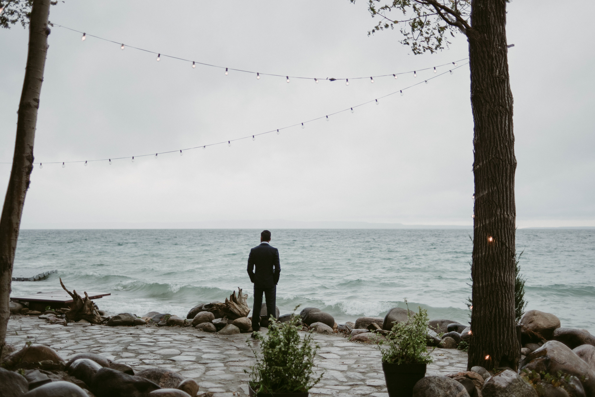 Groom looking out onto lake waiting for bride