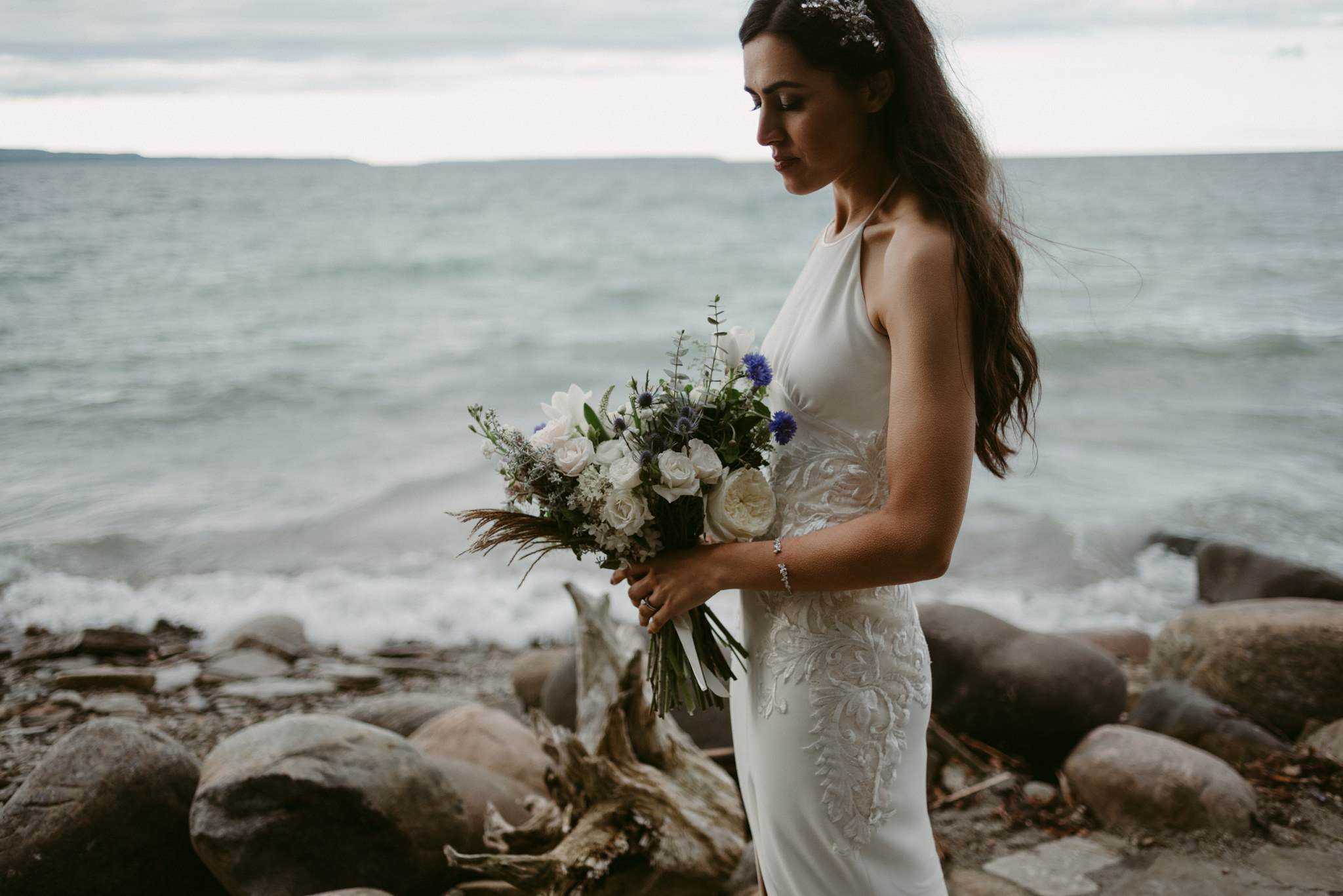 bride holding bouquet by waterfront