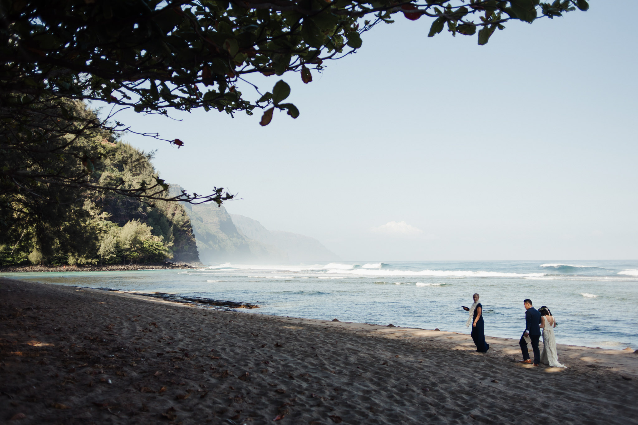 Bride and groom walking on sand on Ke'e beach wedding ceremony