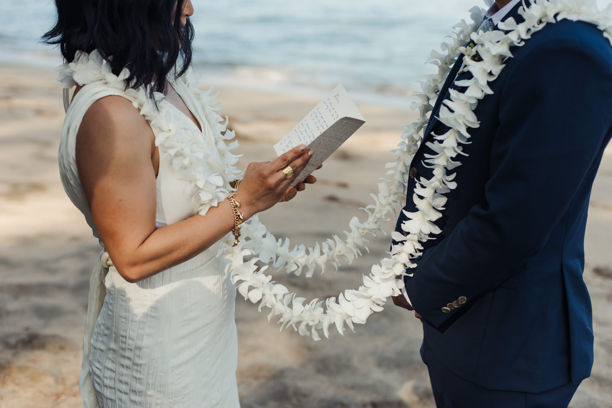 bride reading vows to groom on beach