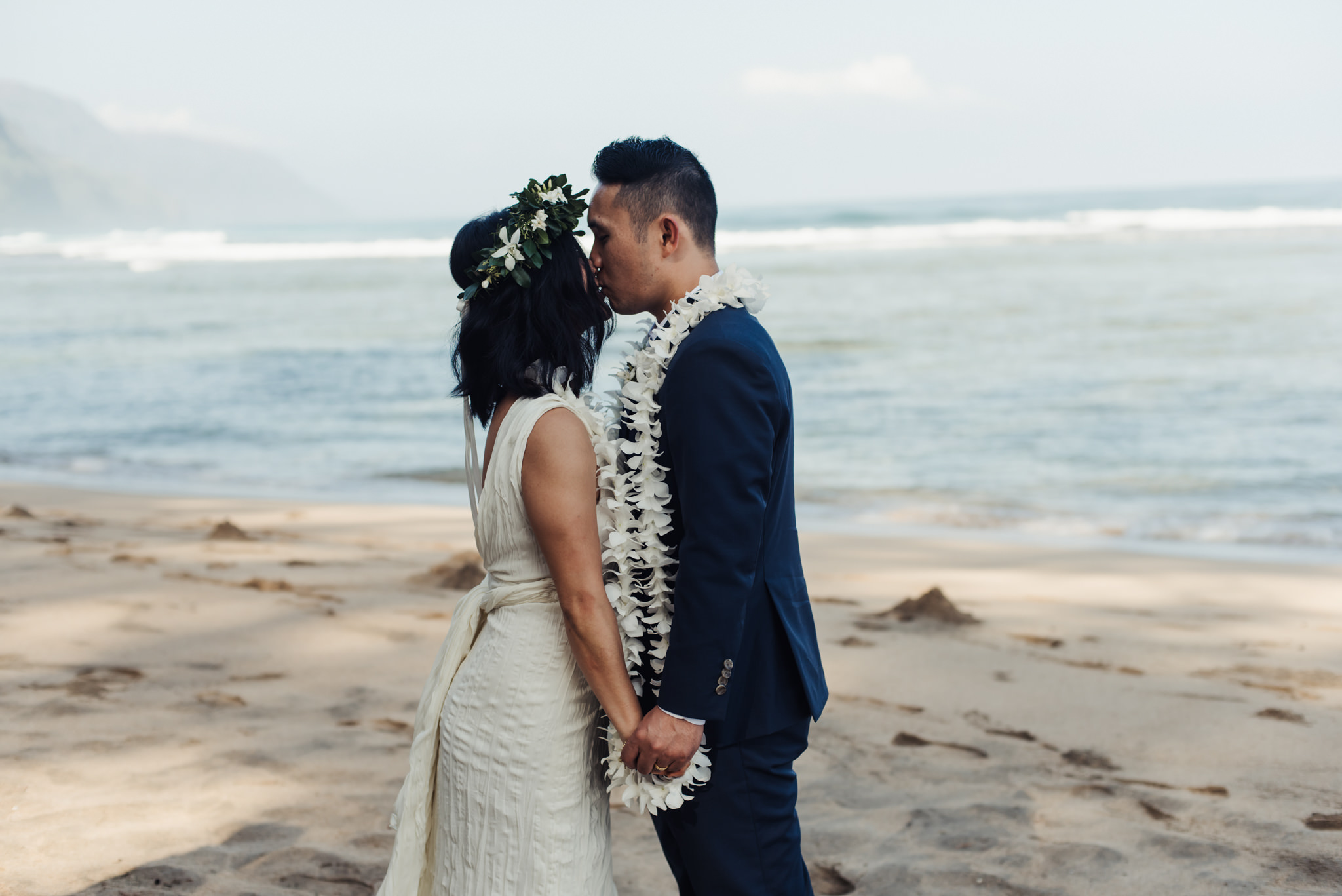 bride and groom kissing on beach in kauai