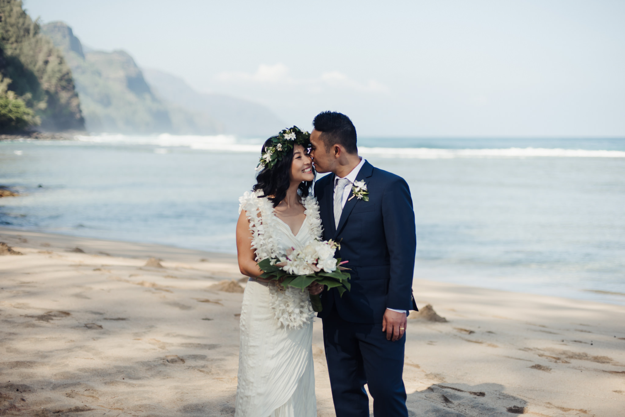 groom kissing bride on beach