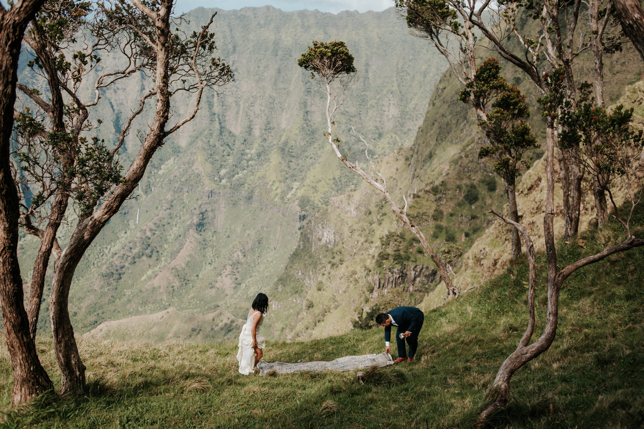 bride and groom setting up picnic with view of Na pali Coast Kauai