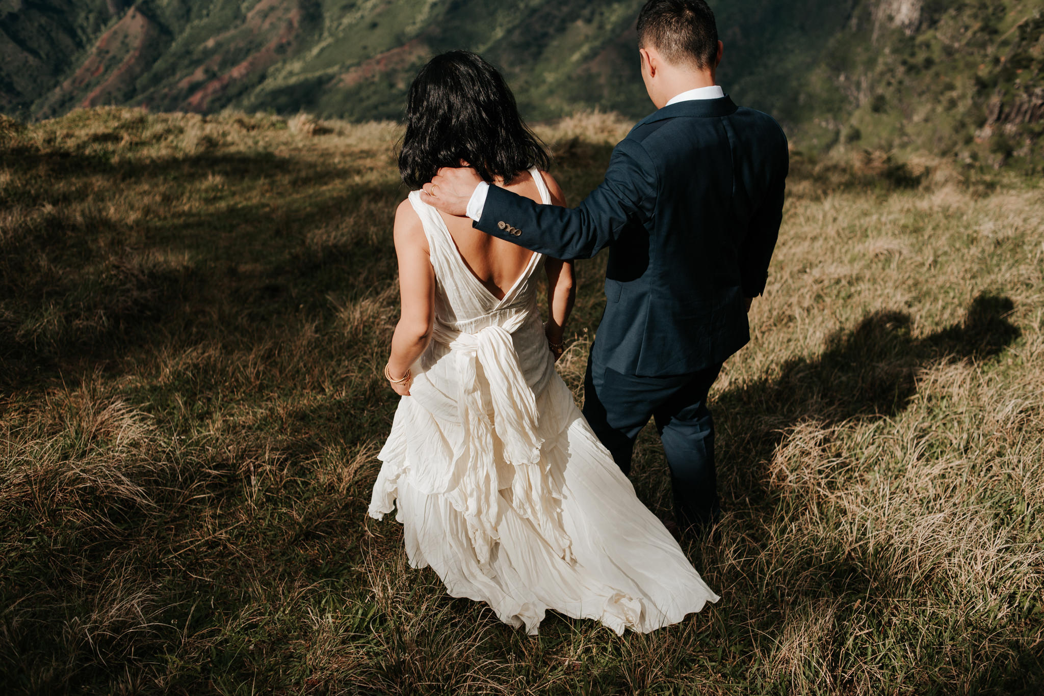 bride and groom walking on cliff edge in kauai