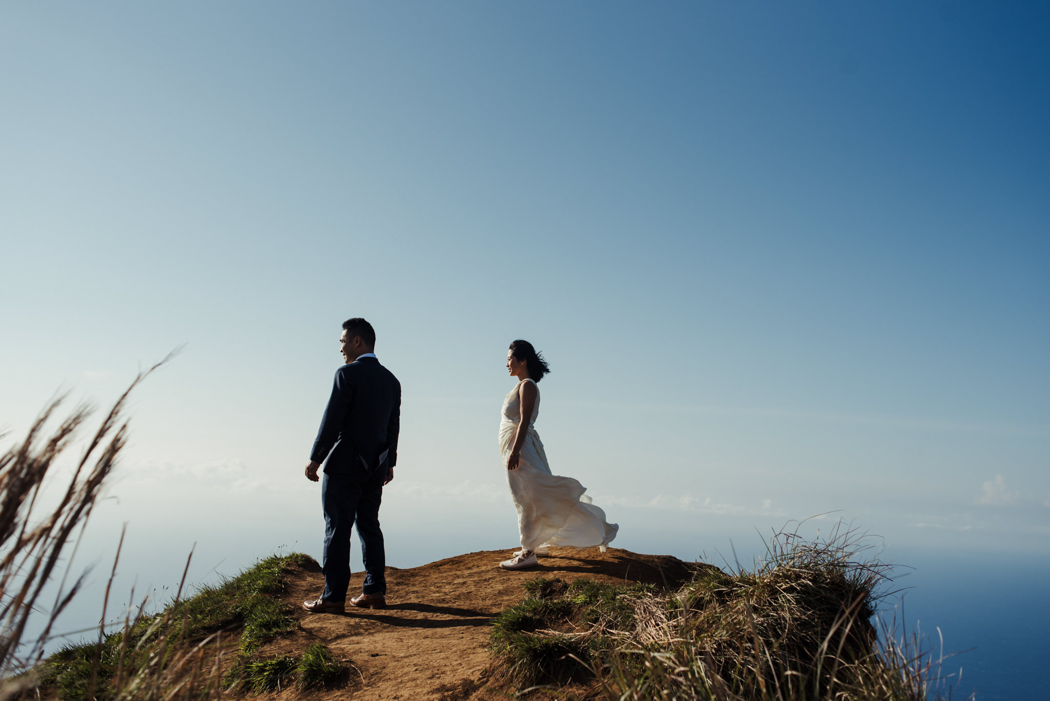 bride and groom on edge of cliff in kauai