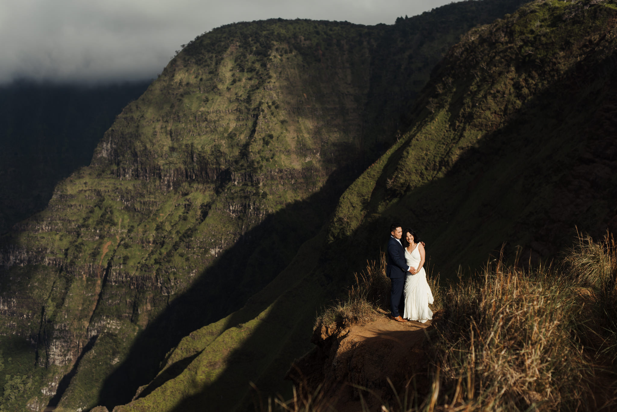 Bride and groom standing in front of cliffs in Kauai elopement