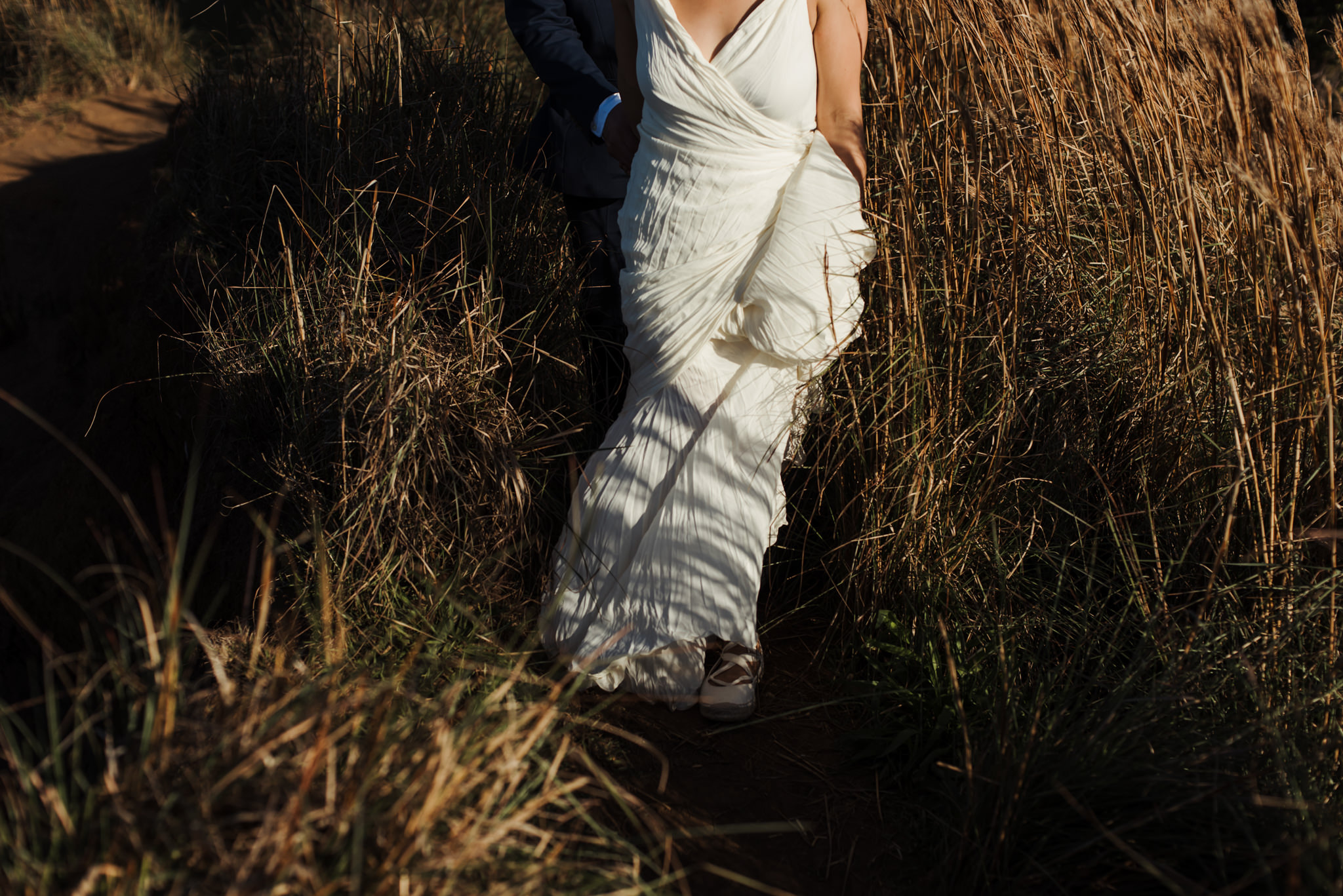 bride holding wedding dress while hiking