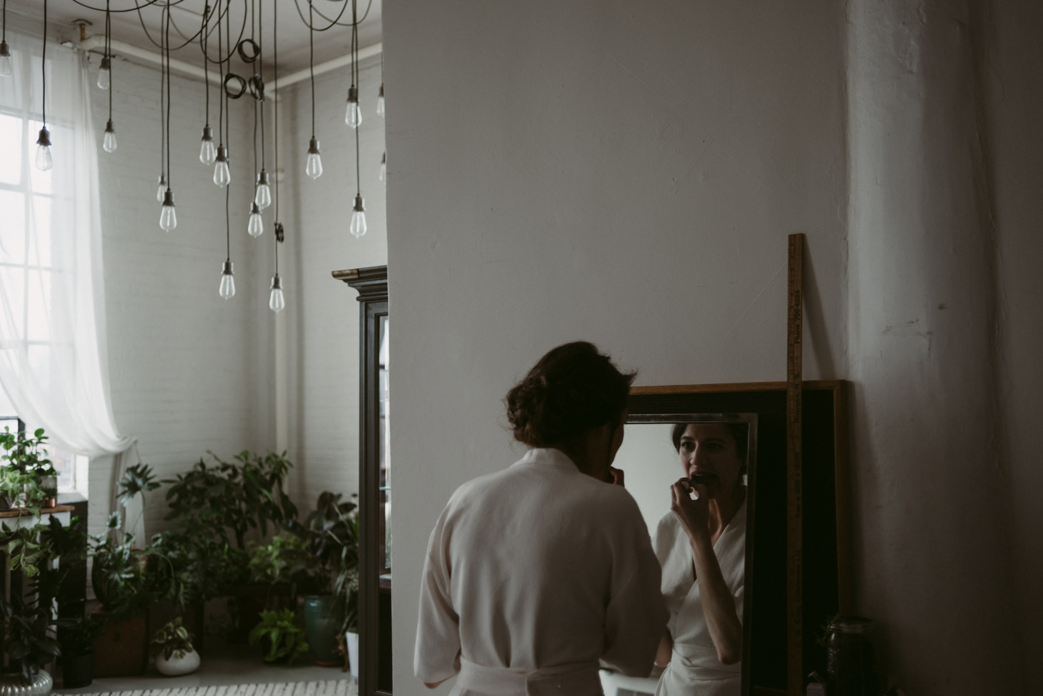 Bride looking in mirror doing makeup