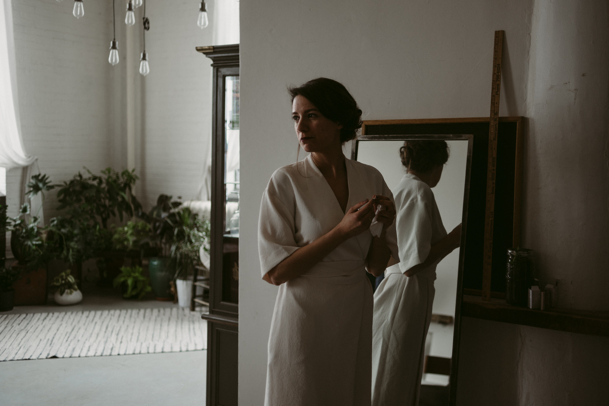 Bride looking in mirror doing makeup