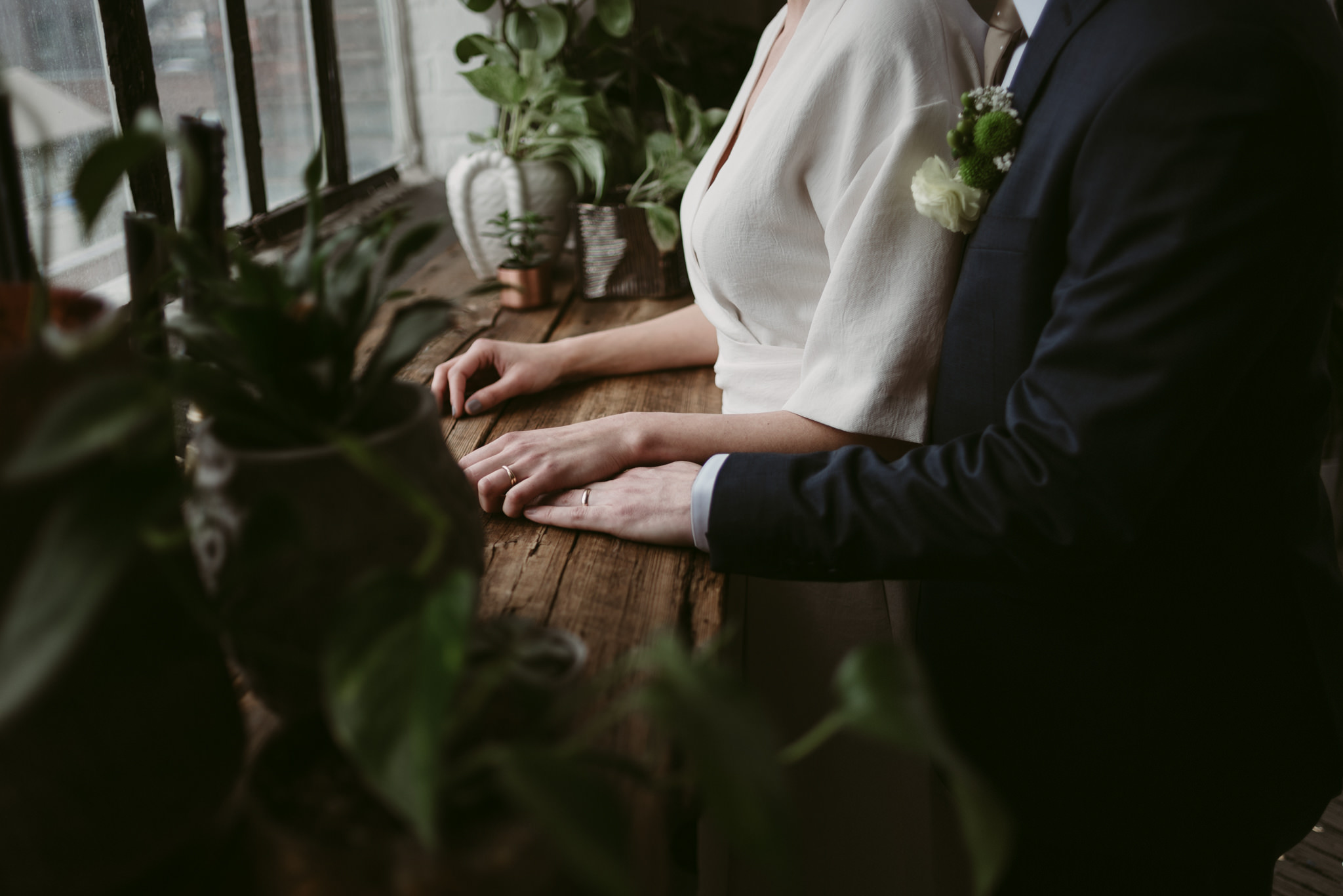 Groom hugging bride from behind, holding hands