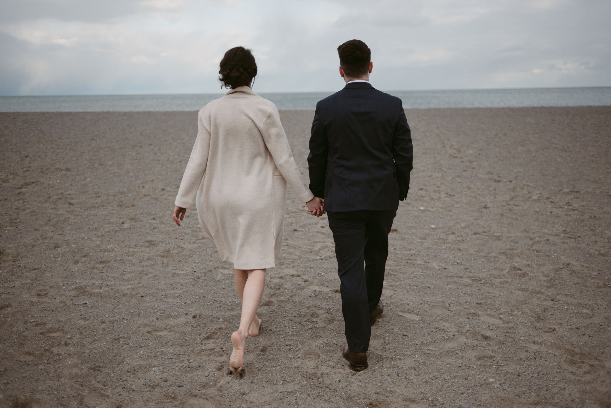 Bride and groom walking on beach holding hands