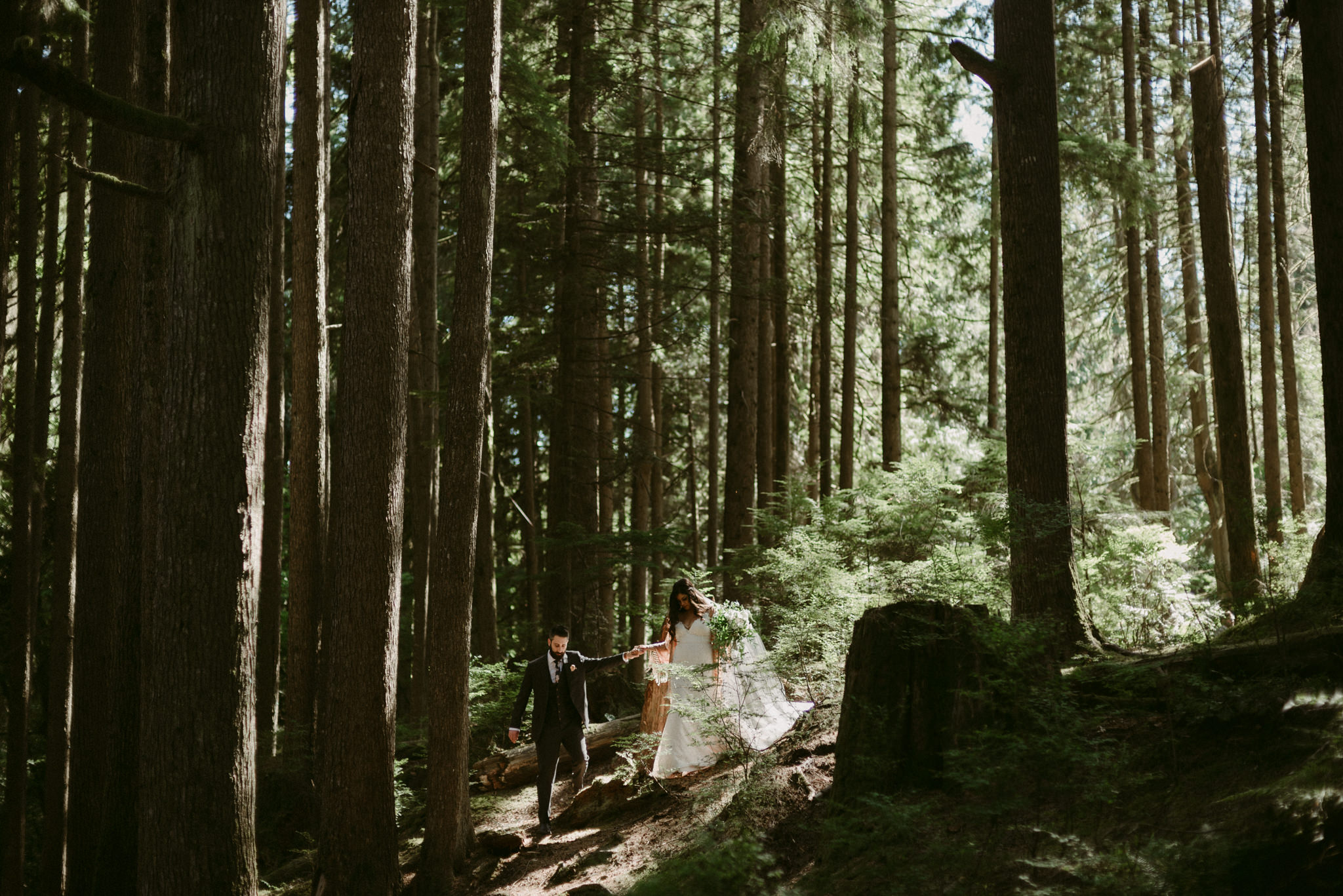 Bride and groom walking in light filled forest