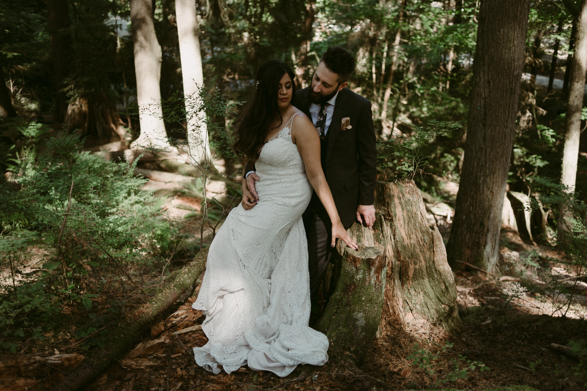 bride and groom sitting on tree stump on forest