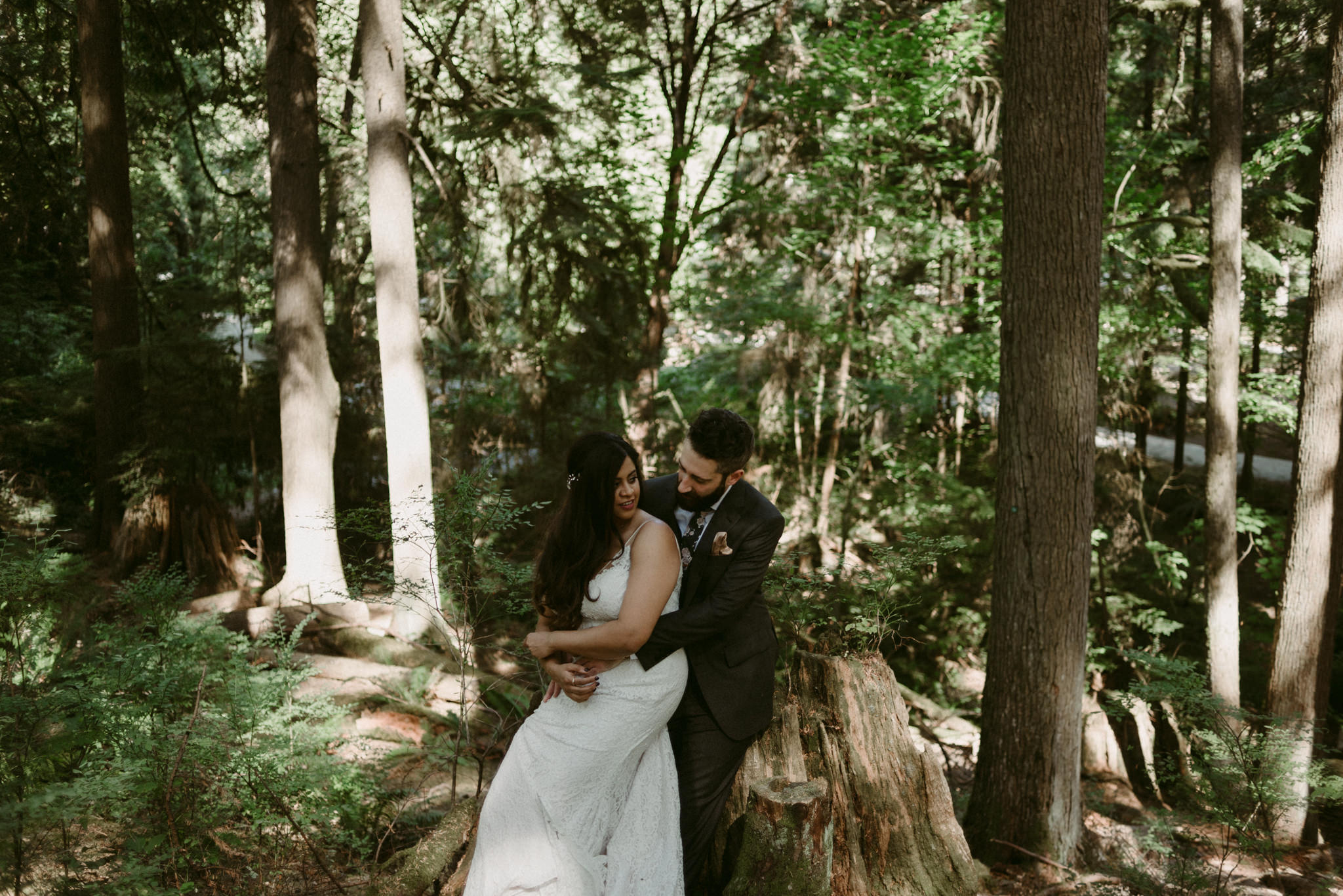 bride and groom sitting on tree stump on forest