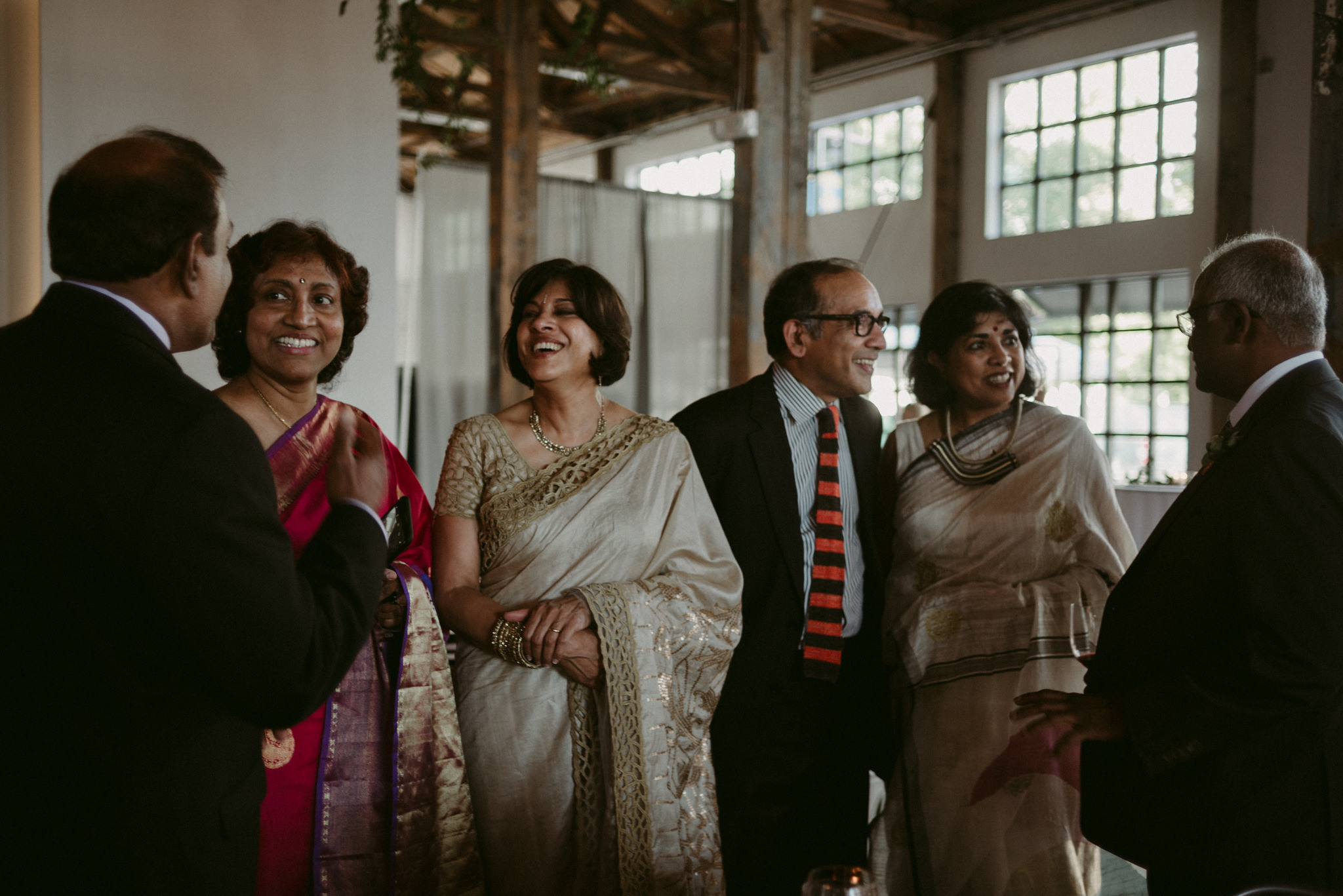 indian guests in saris laughing and talking during wedding reception