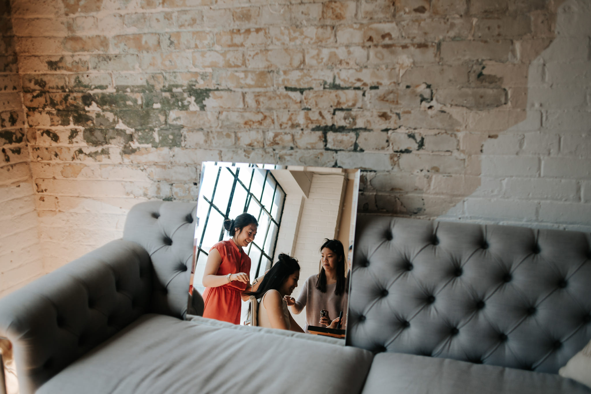 sisters doing hair of bride in old loft