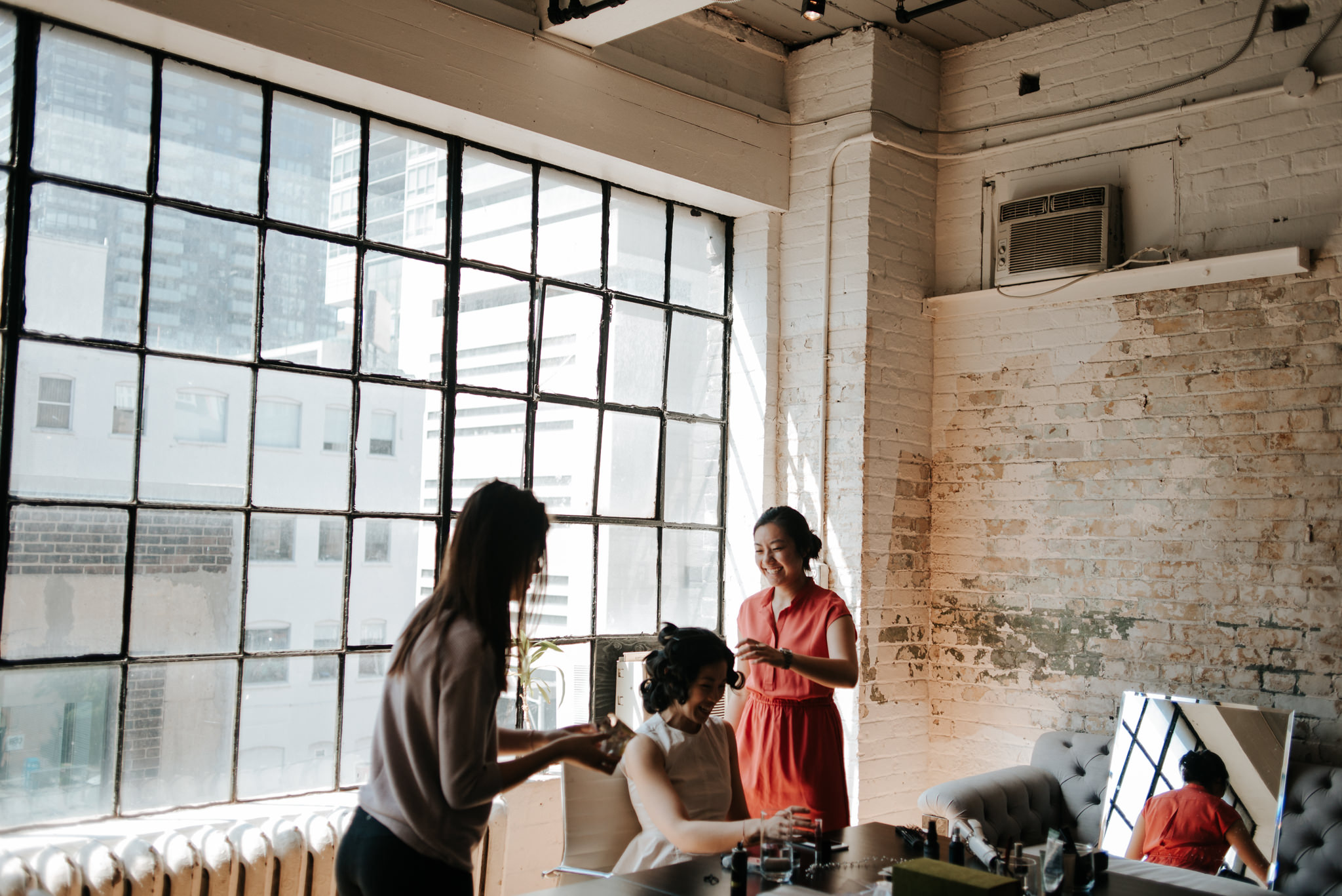 sisters doing hair of bride in old loft