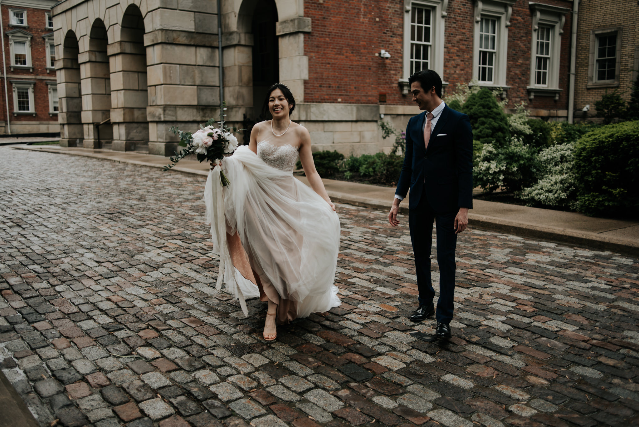 bride and groom hugging and smiling in front of old building