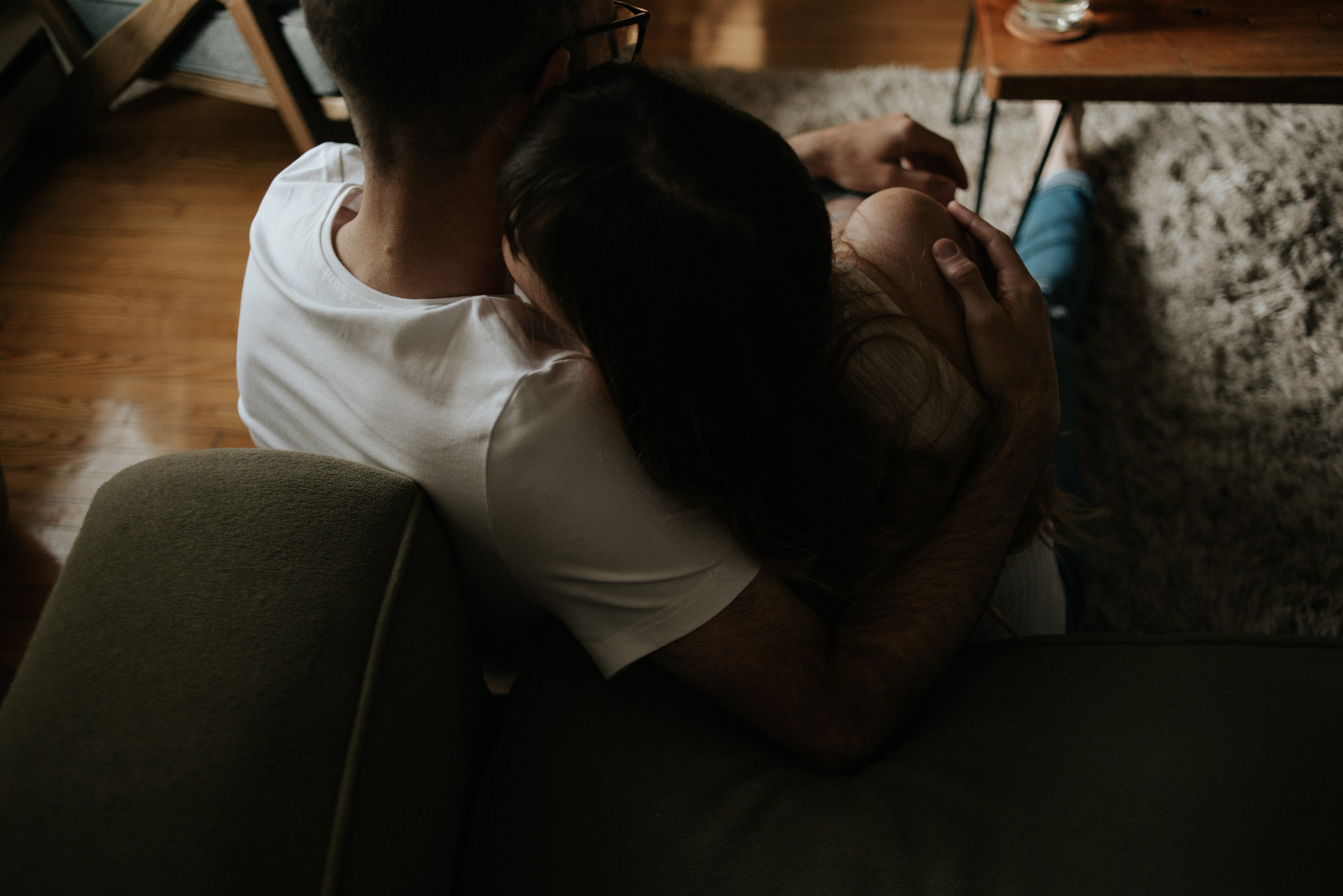 Couple sitting on floor of apartment hugging