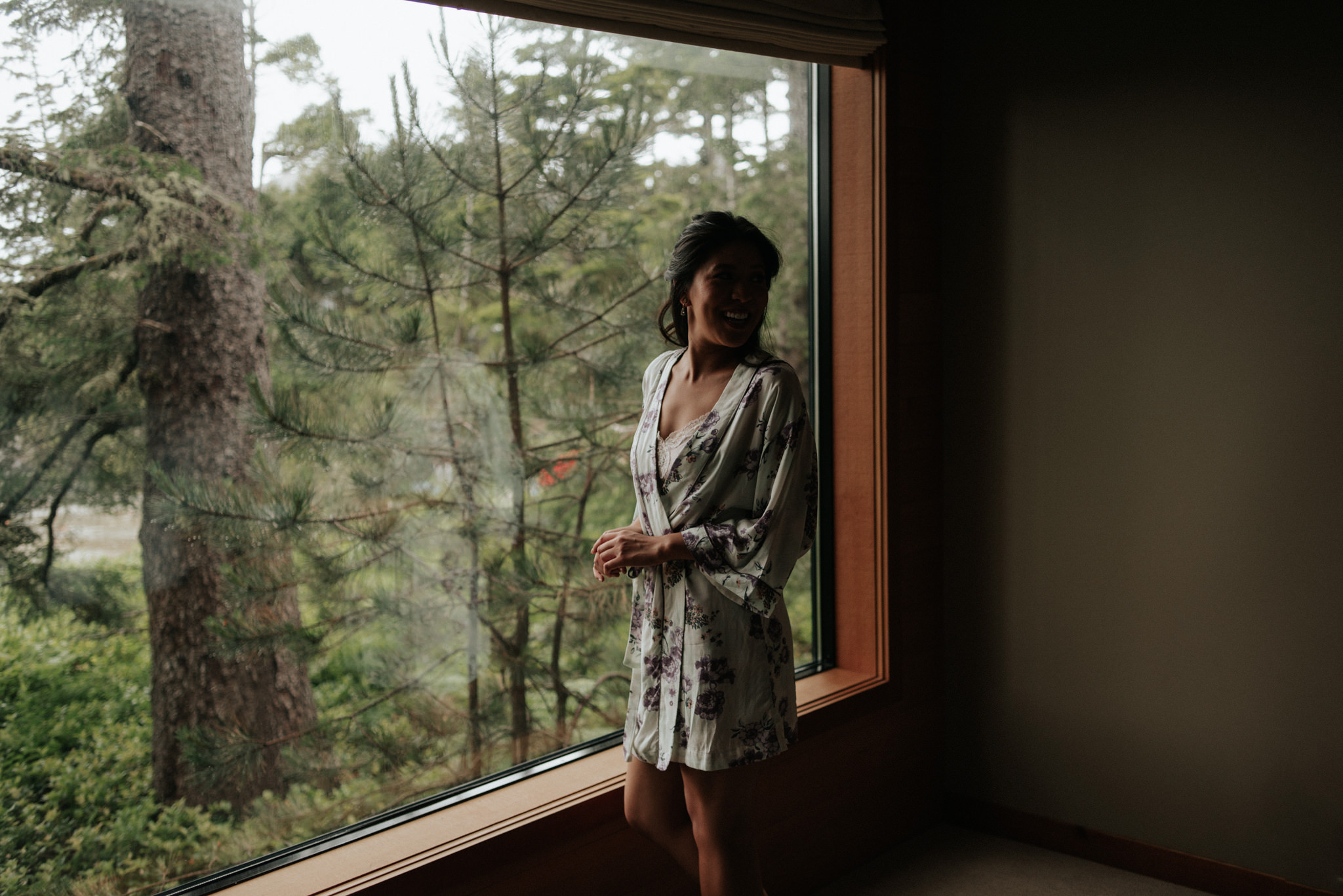 bride getting ready by window at Wickaninnish Inn for her Tofino Elopement