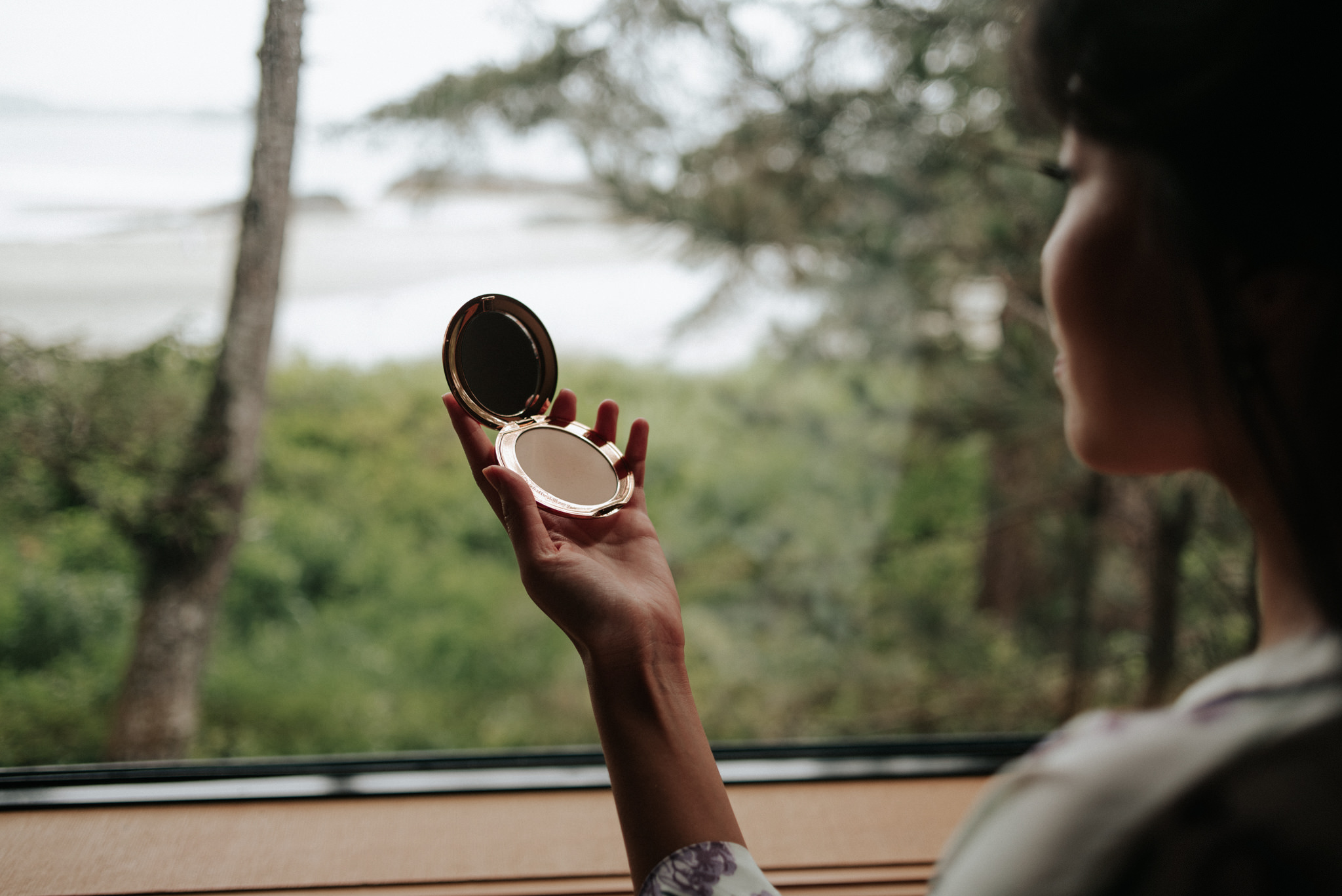 bride getting ready by window at Wickaninnish Inn for her Tofino Elopement