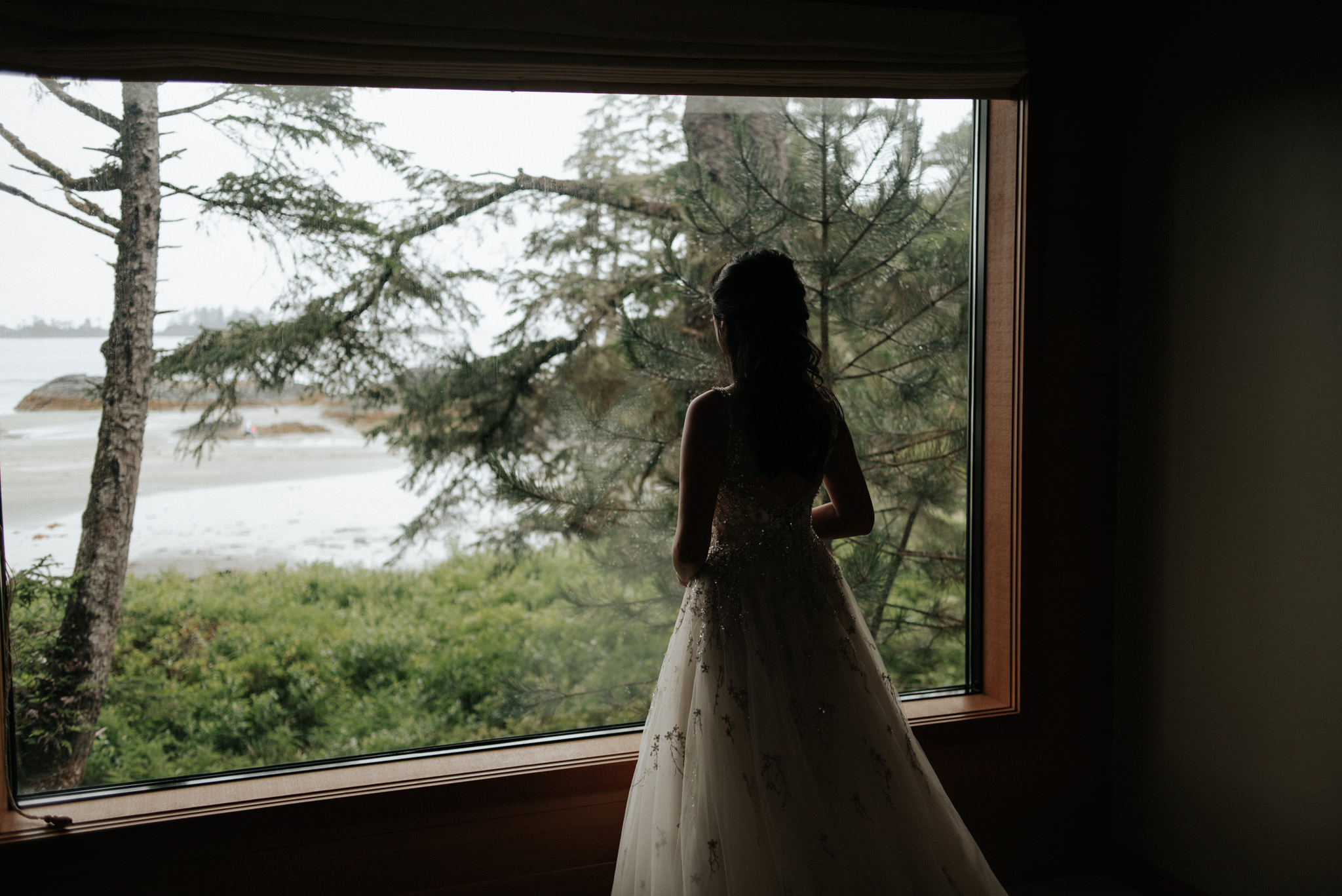 bride in wedding dress by window at Wickaninnish Inn for her Tofino Elopement