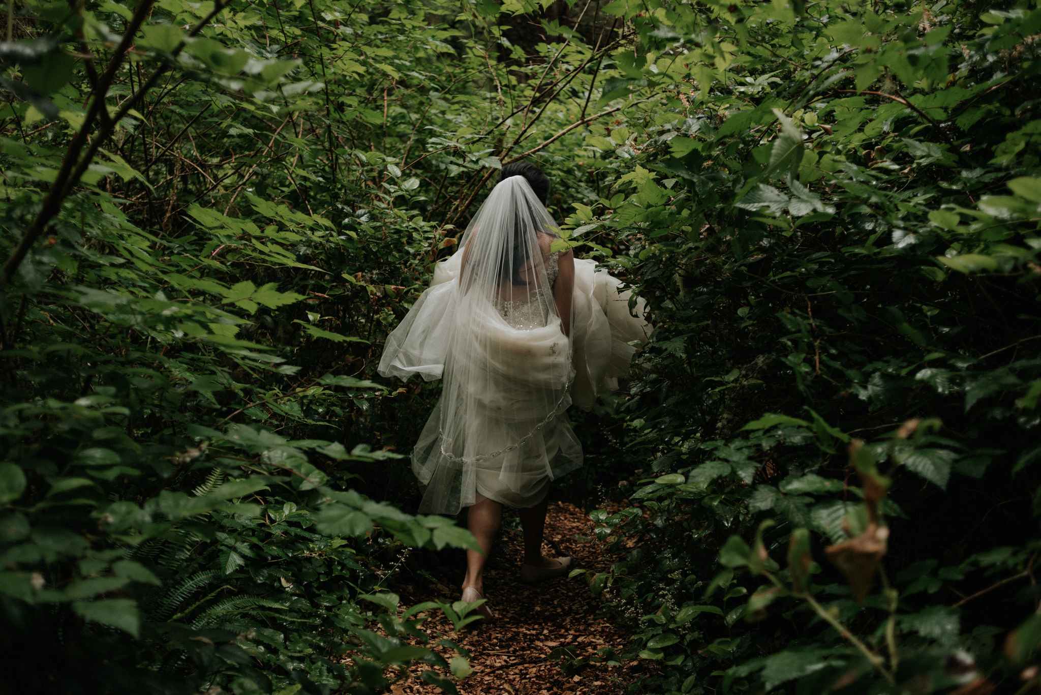 bride in wedding dress walking on forest path